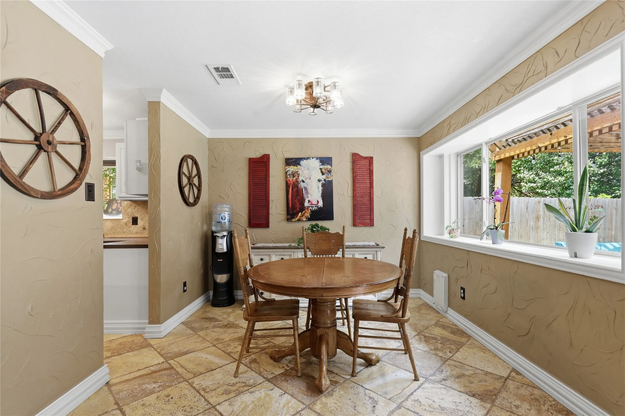 Dining area featuring a bay window, crown molding, and neutral-toned textured walls