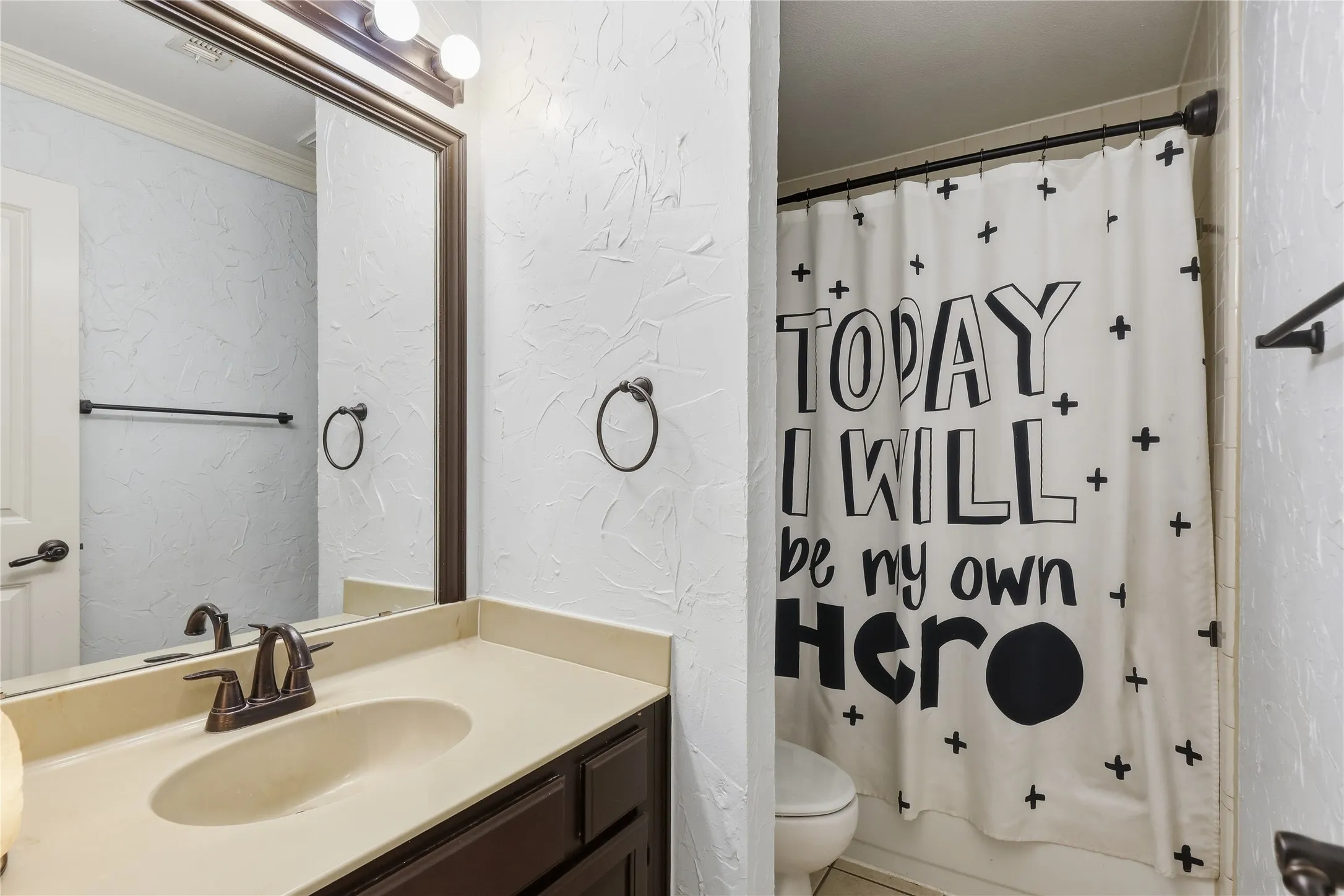 Bathroom featuring a built-in vanity with an integrated sink and bronze-finish faucet, a framed mirror, and a shower with an opaque curtain