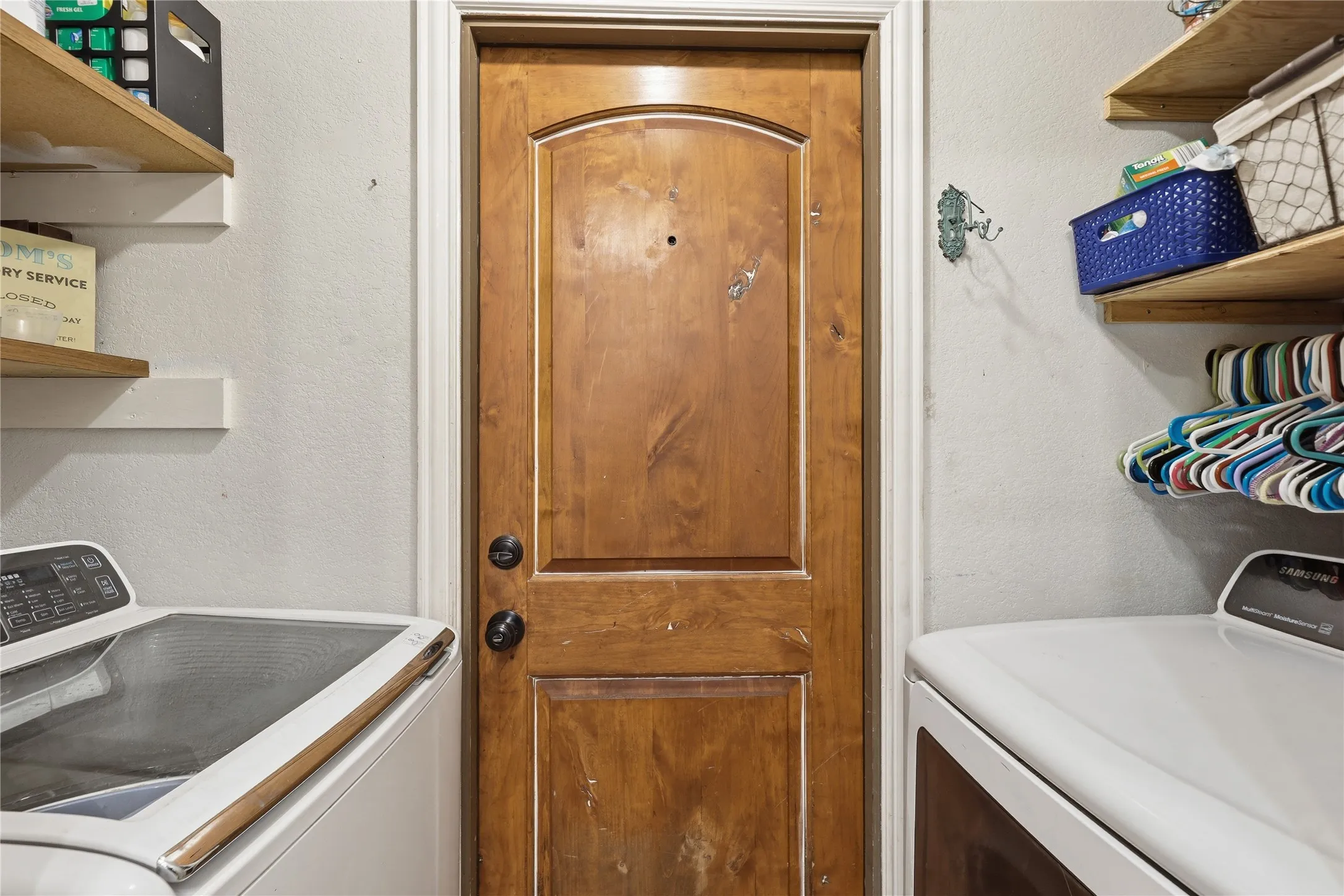 Solid wood arched panel door with dark hardware, flanked by built-in wood shelving