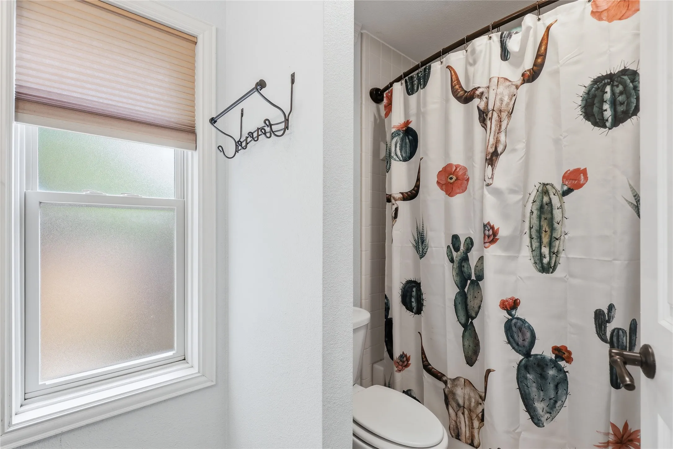 Bathroom featuring a white framed window with frosted glass and a cellular shade