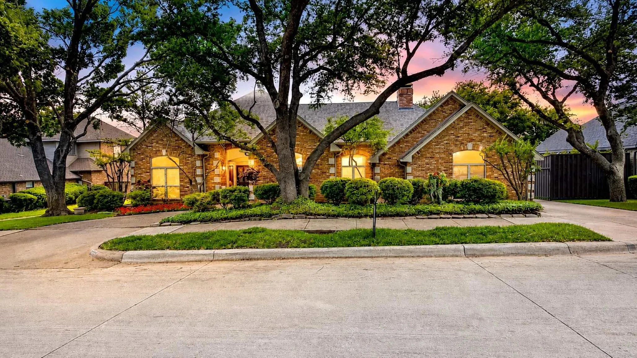 Classic brick exterior under mature shade trees with circular drive and welcoming entry.