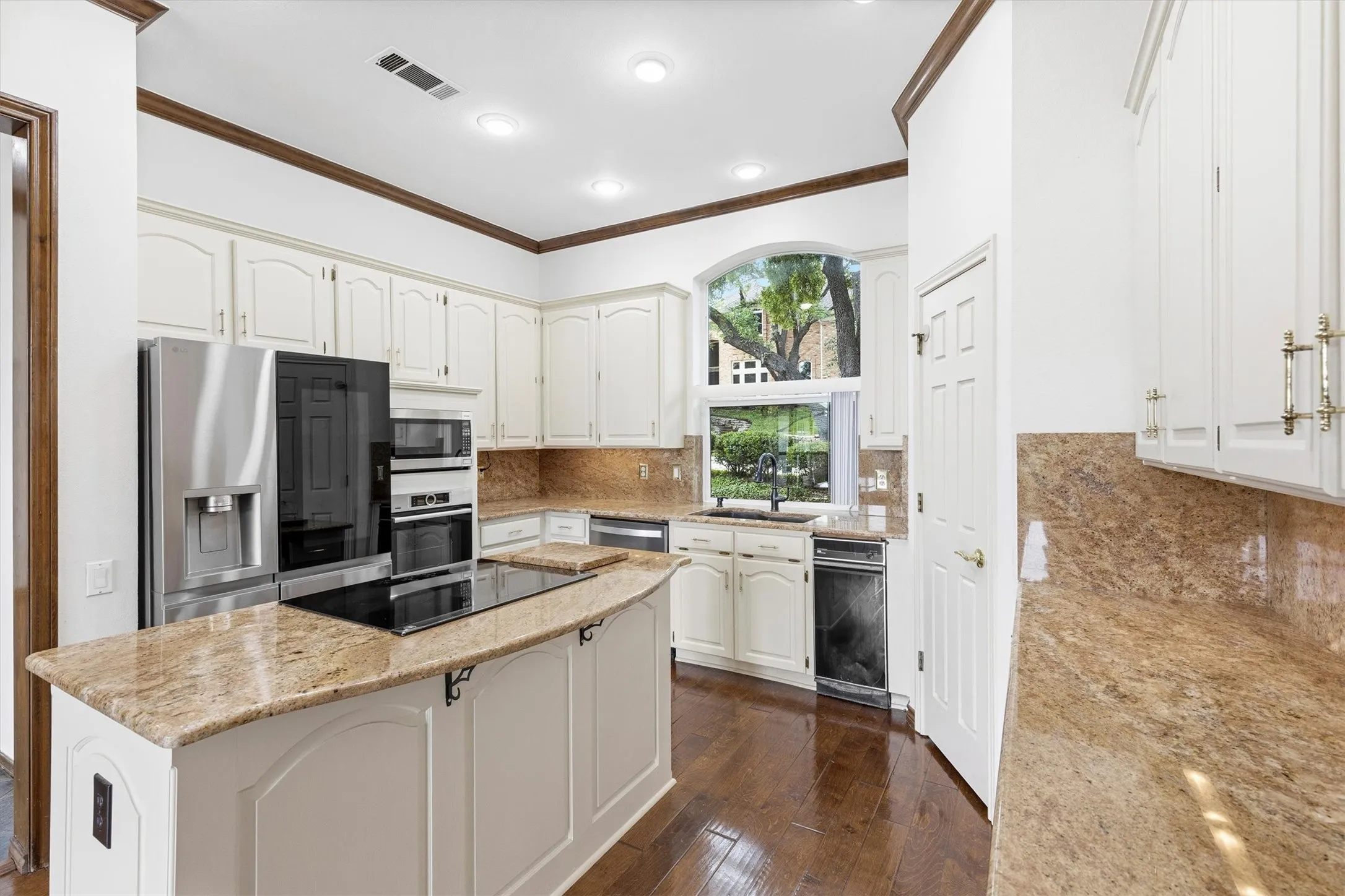 Kitchen with granite countertops, center island cooktop, and stainless steel appliances.