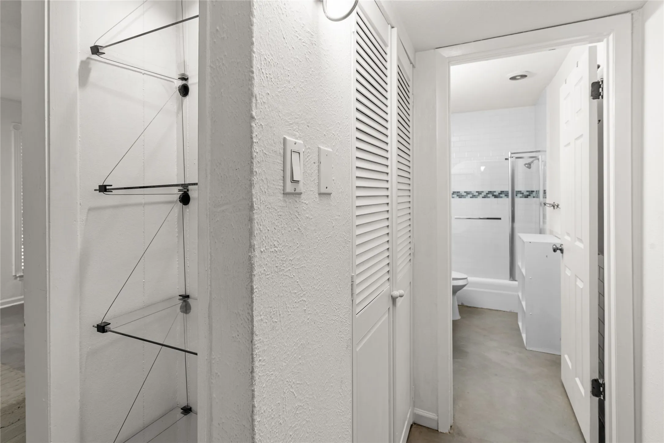 Hallway featuring built-in shelving, louvered utility closet, and recessed lighting