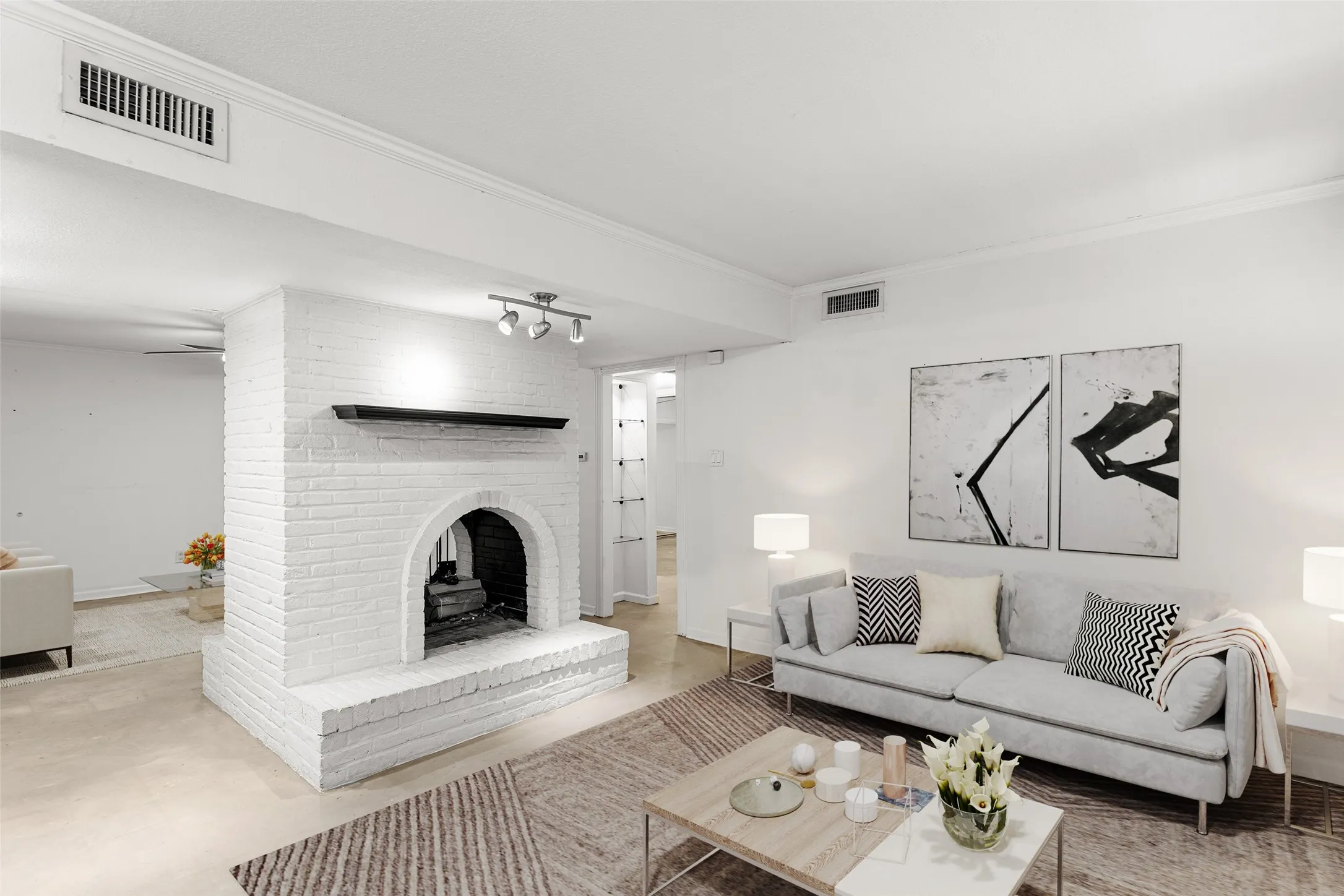 Virtually Staged Living area featuring a painted brick fireplace with an arched firebox, a dark mantel, and track lighting