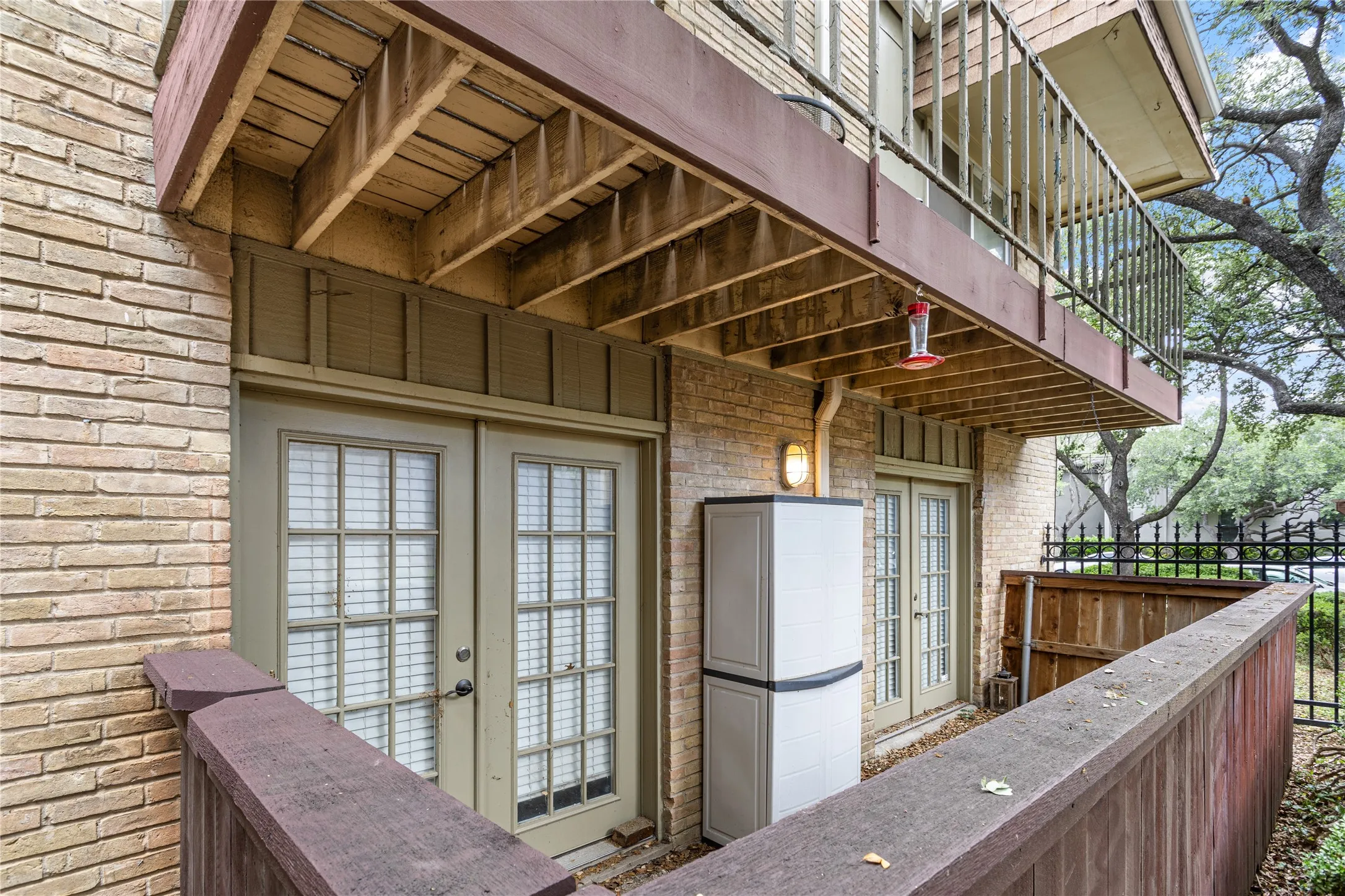 Ground-level patio featuring brick exterior, a pair of French doors with gridded lites, and a privacy fence