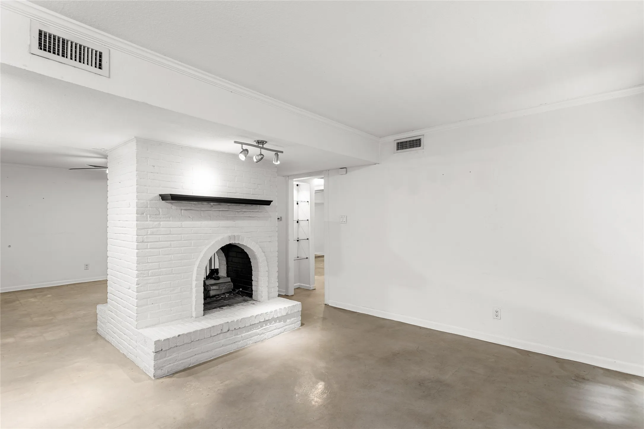 White-painted brick fireplace featuring an arched firebox opening and a dark-toned mantel
