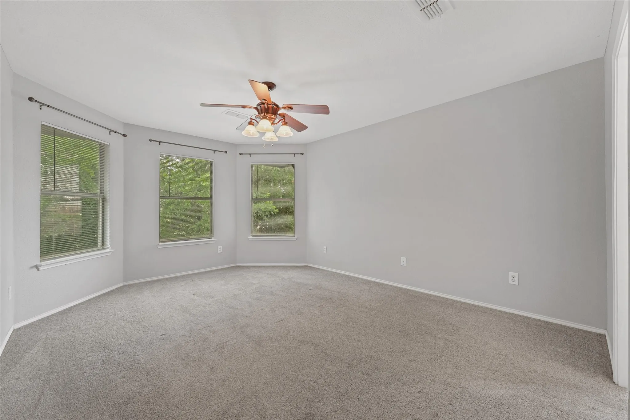 Recessed wall section featuring three windows, neutral gray walls, and gray carpet