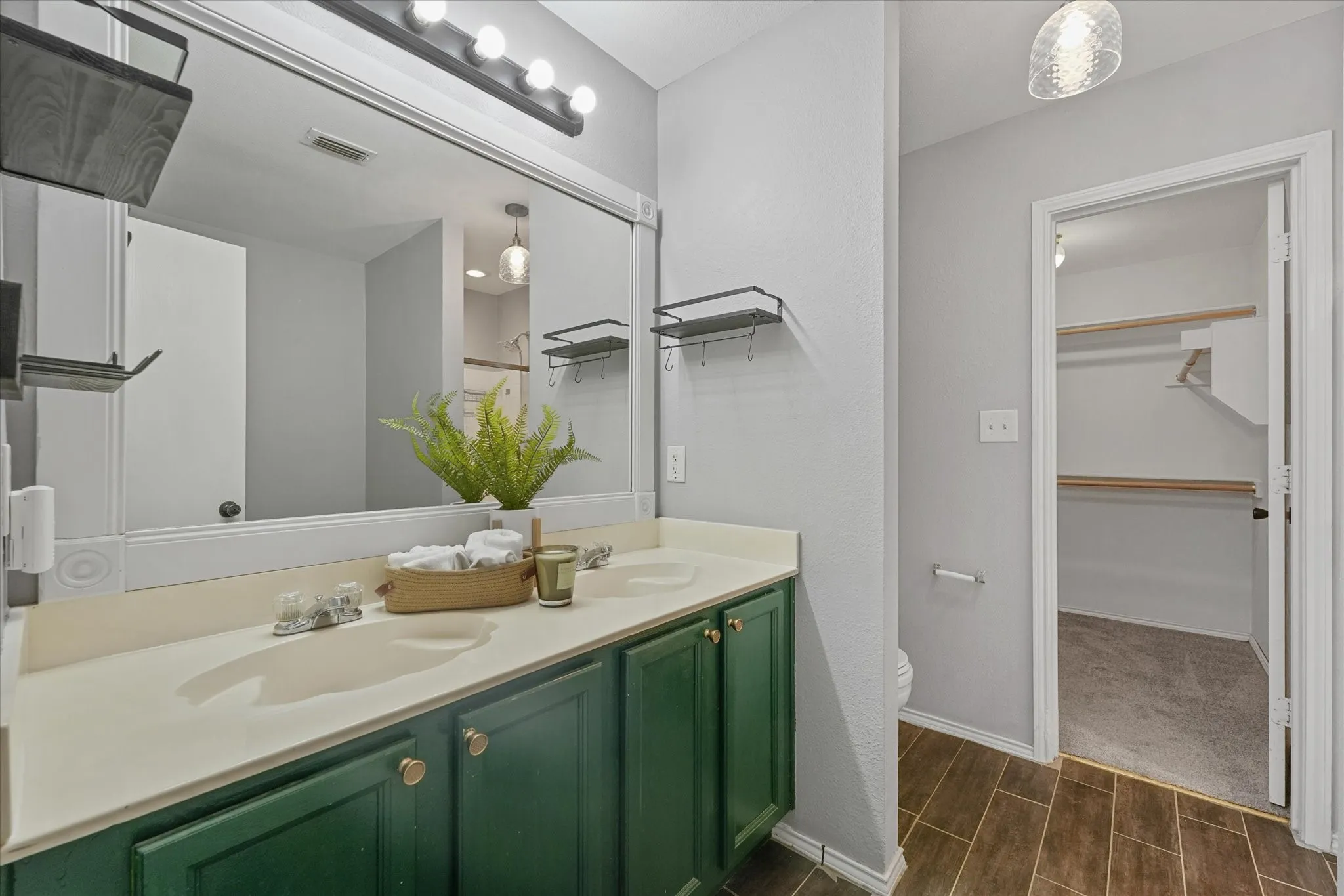 Bathroom featuring a double vanity with green cabinetry, a light-toned countertop, and dual integrated sinks