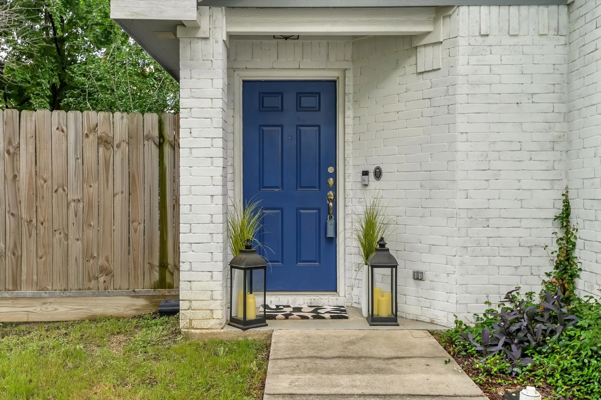 White brick exterior featuring a vibrant blue entry door with polished hardware