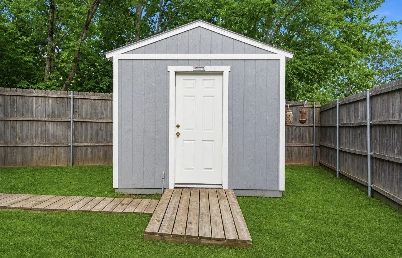 Freestanding shop with gray vertical siding and white trim equipped with AC and electric.
