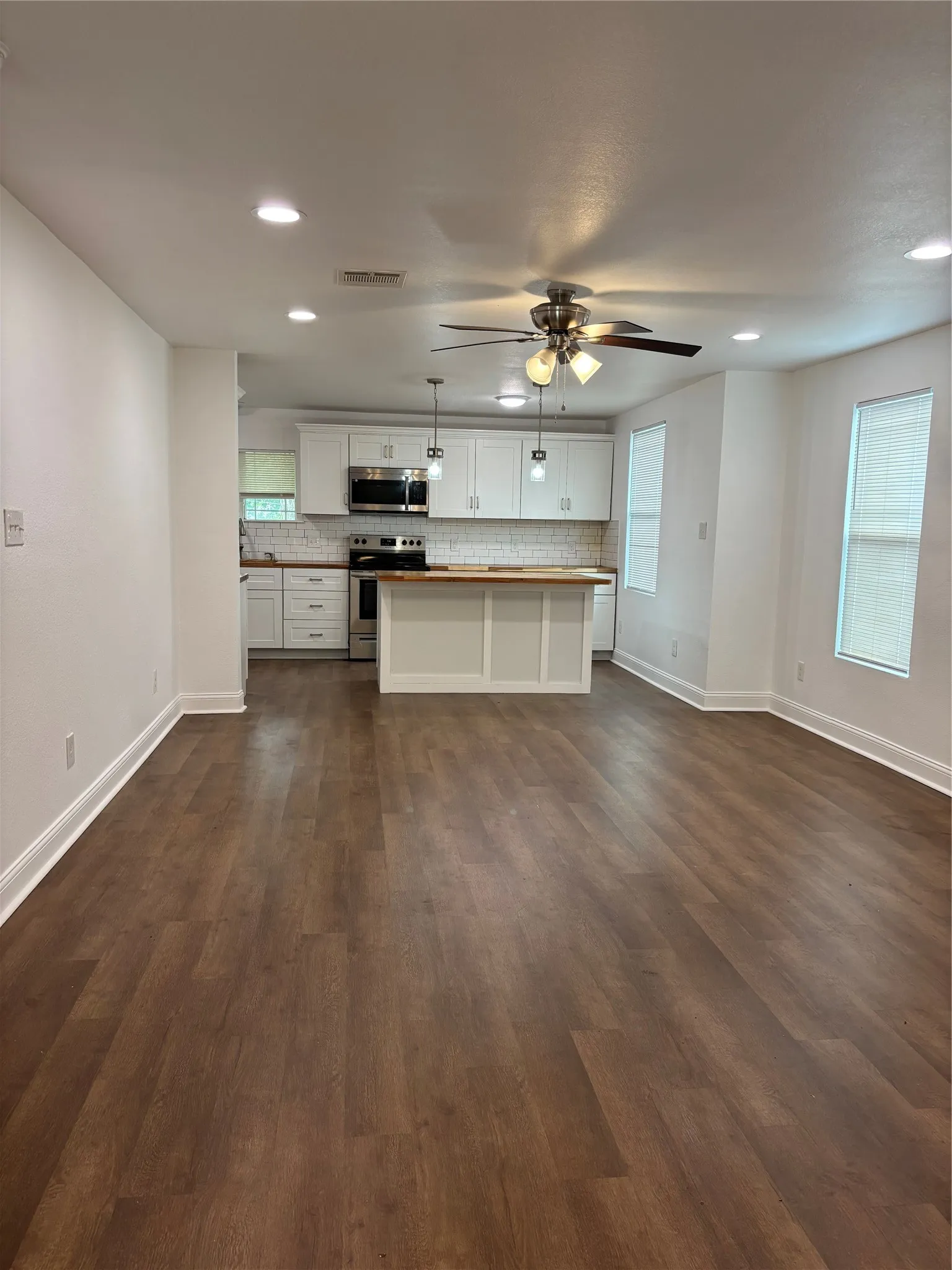 Open-concept living space featuring wood-finish flooring, recessed lighting, and a ceiling fan