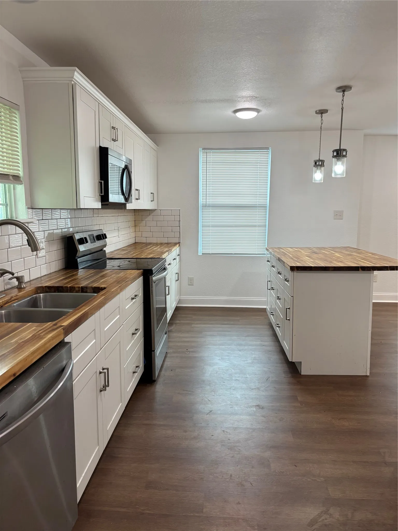 Modern kitchen featuring wood-finish countertops, white shaker cabinetry, and a subway tile backsplash
