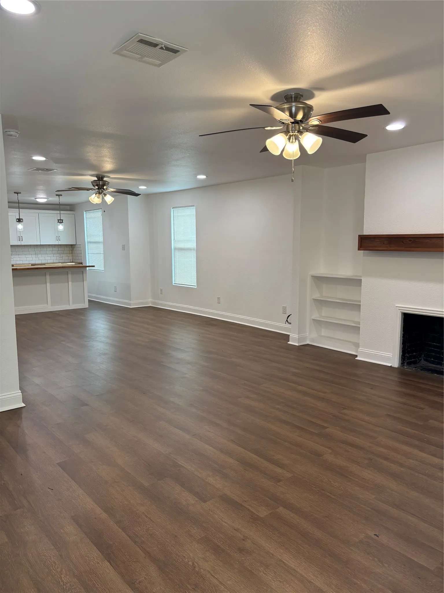 Open-concept living space with wood-finish flooring, recessed lighting, and ceiling fans
