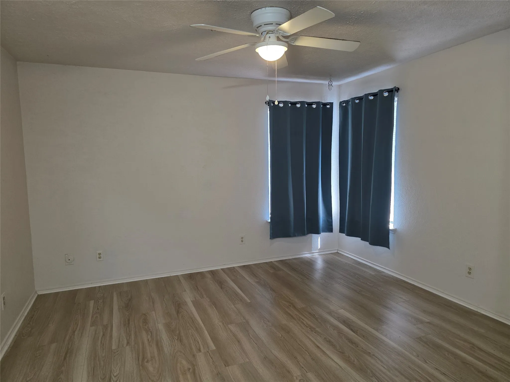 Room featuring wood-finish flooring and a ceiling fan with integrated lighting