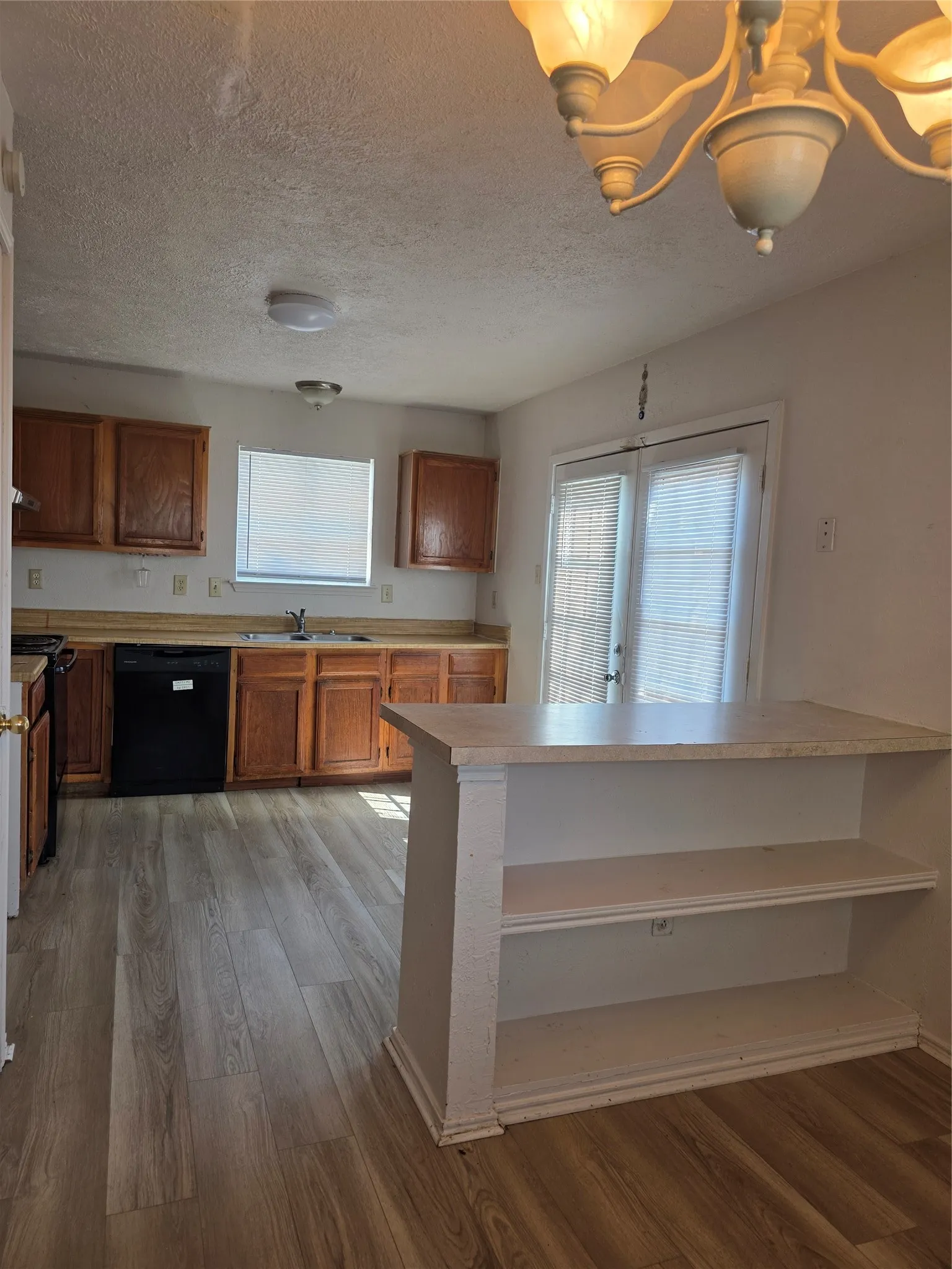 Kitchen featuring wood-finish flooring, wood cabinetry, a breakfast bar with open shelving, and a double-door exterior entry