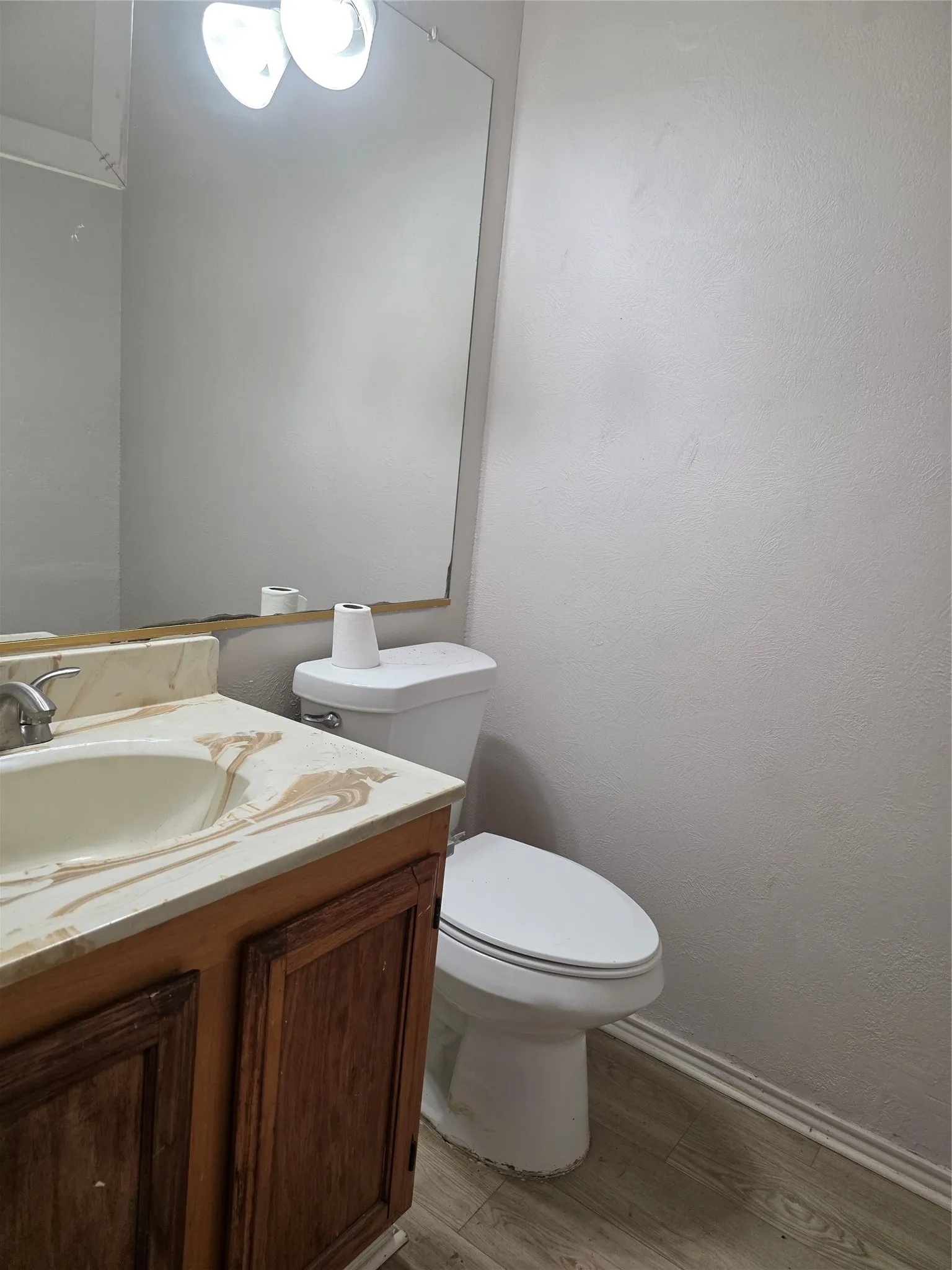 Wood-finish flooring, white walls, and a wood vanity with a built-in sink