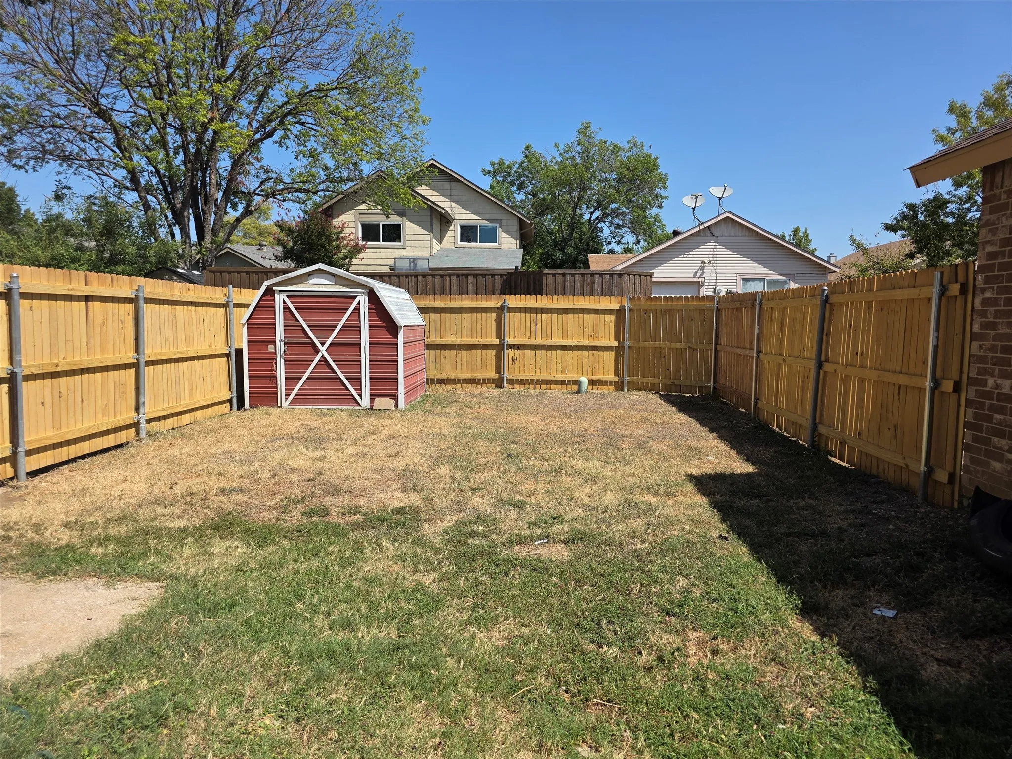 Enclosed backyard space featuring a wood privacy fence and an accessory storage shed