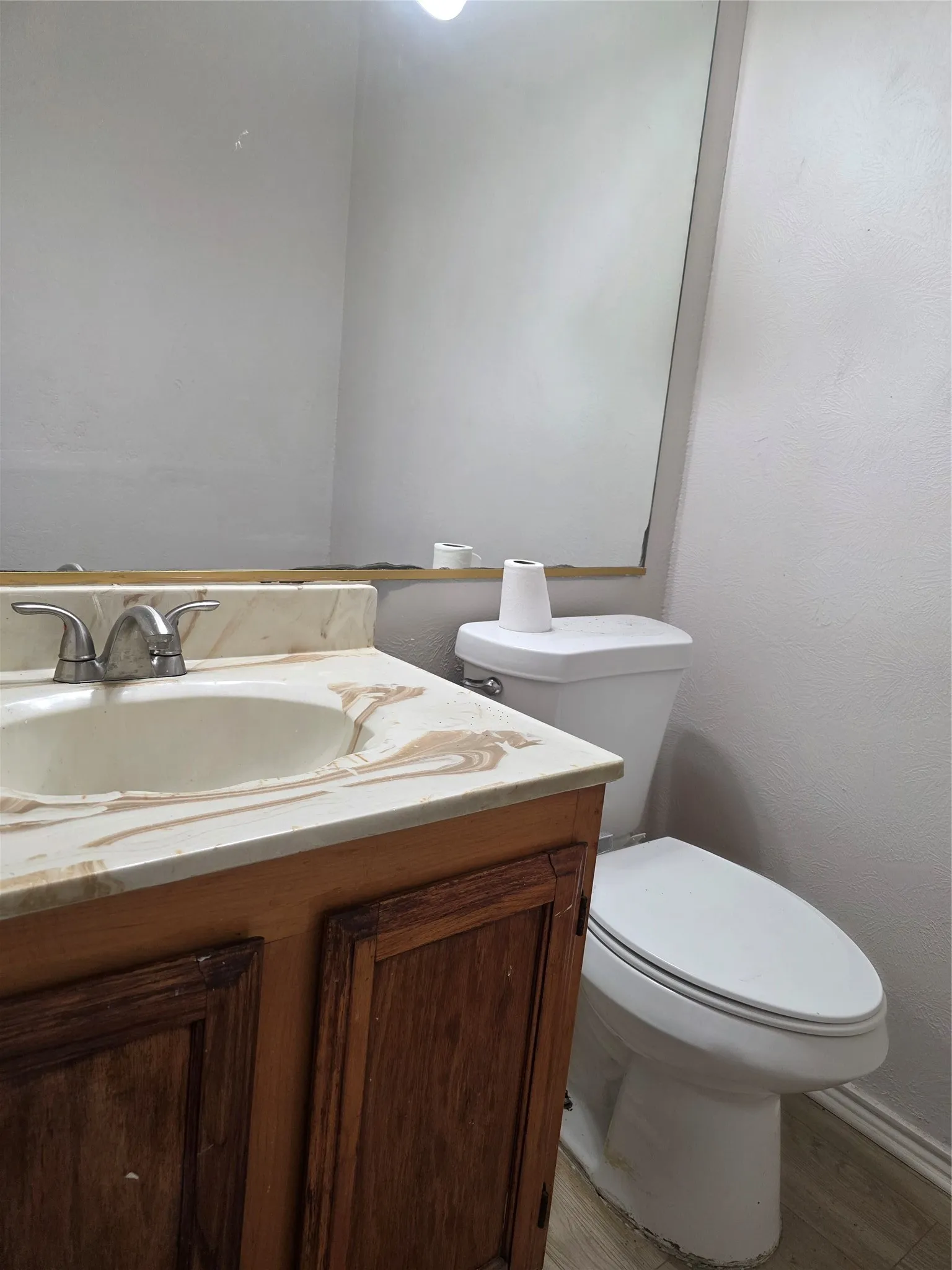 White vanity with integrated sink, patterned countertop, and wood-finish cabinetry