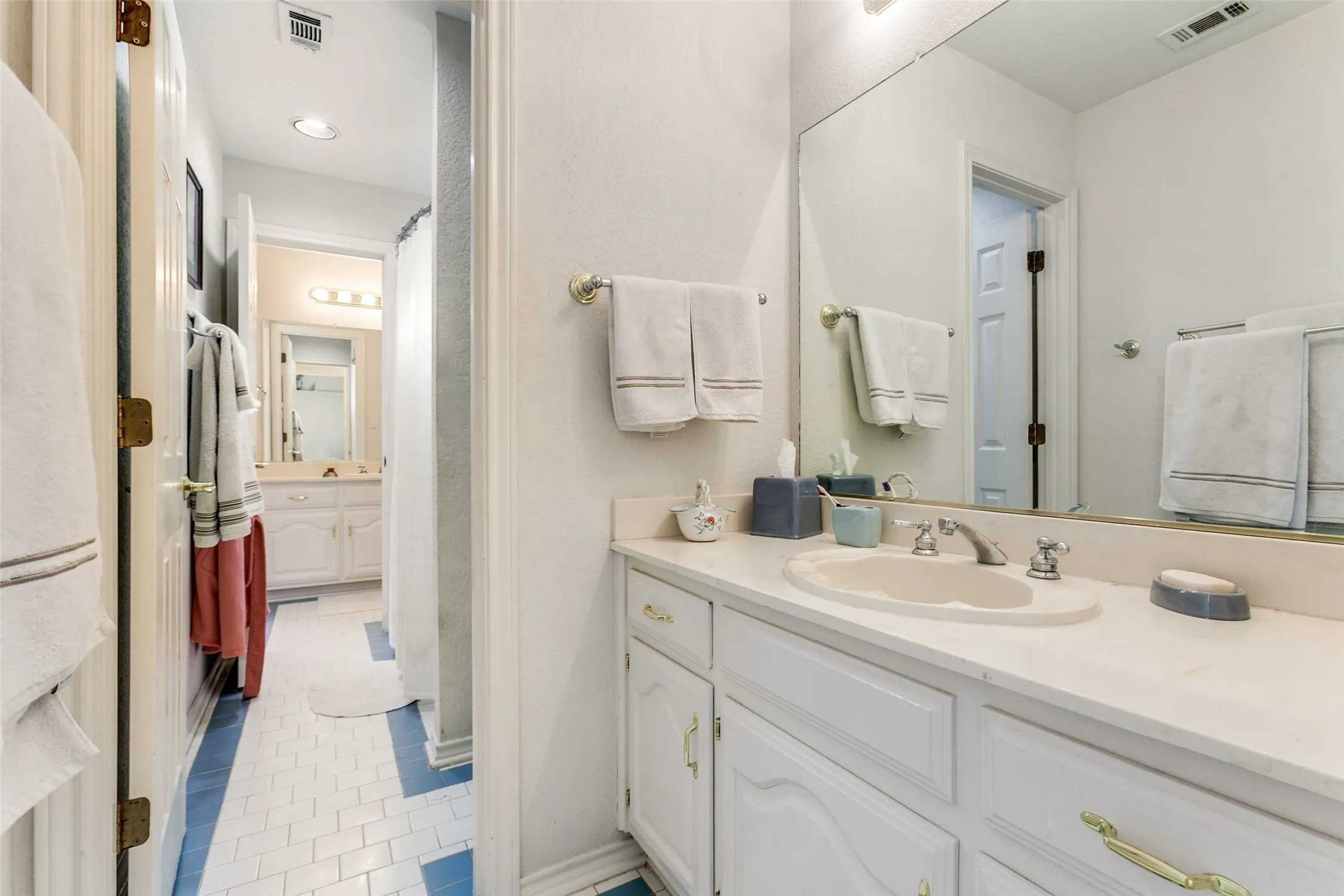 Bathroom featuring a white vanity with an integrated sink, polished chrome faucet, and a large wall-mounted mirror