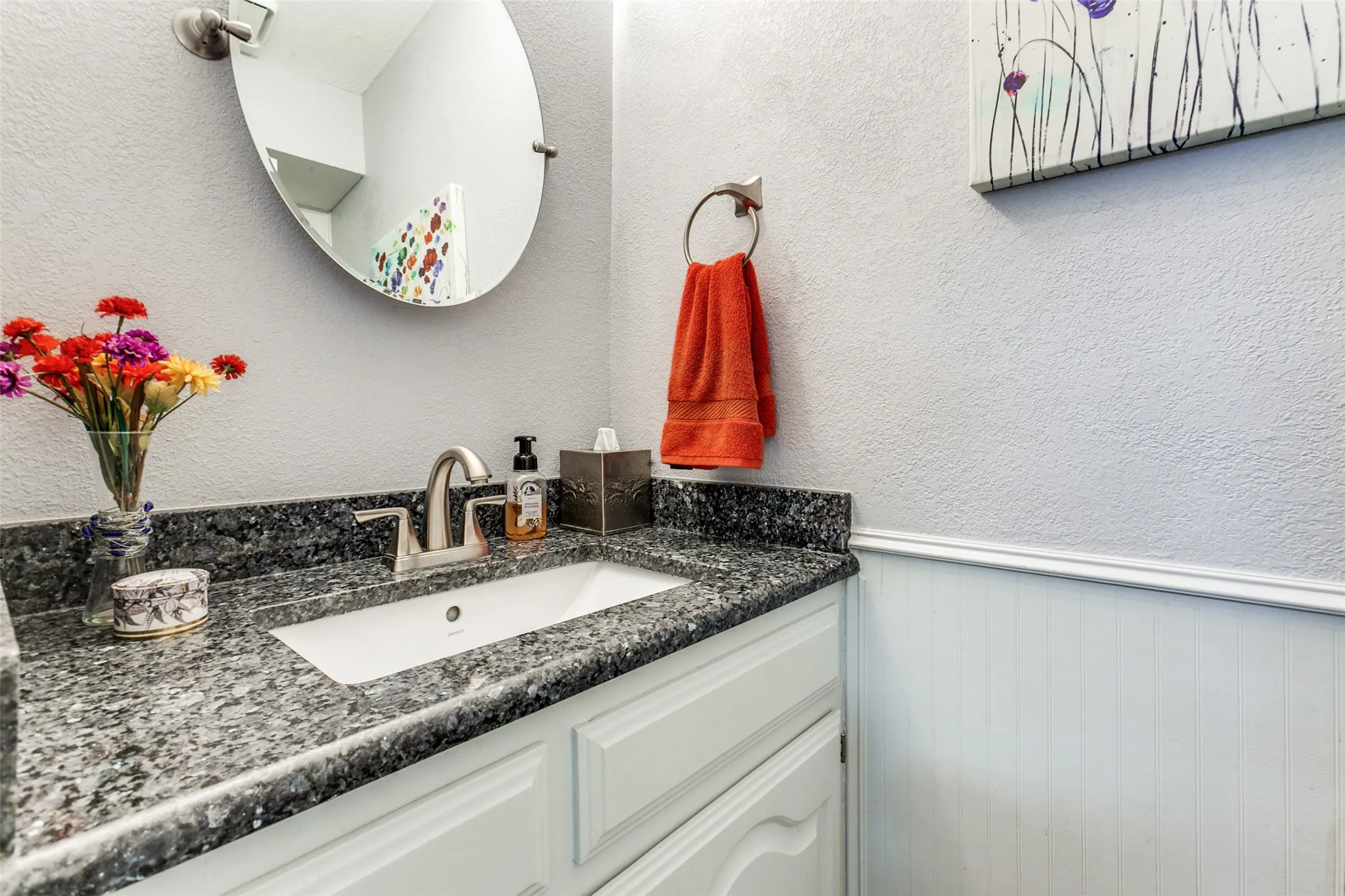 Bathroom vanity featuring a speckled countertop, undermount sink, and brushed nickel faucet