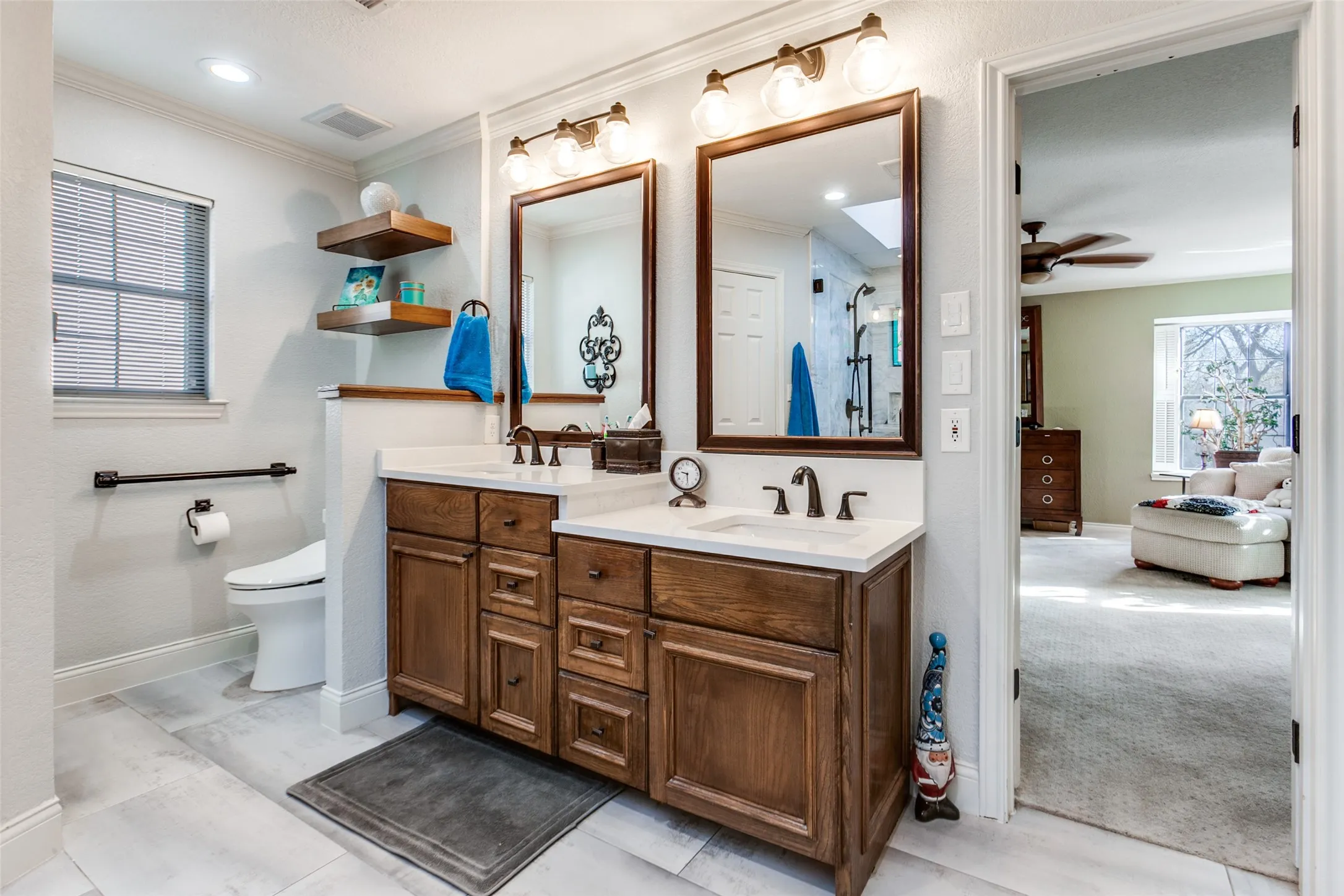Dual vanity with wood-finish cabinetry, white countertops, and matte black fixtures