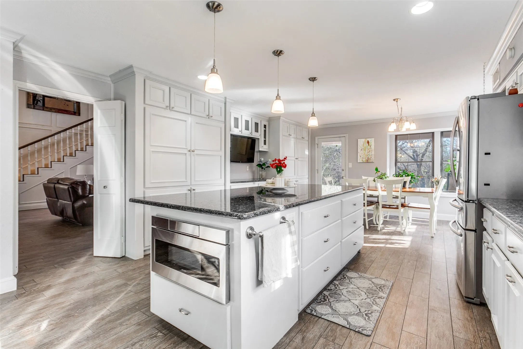 Kitchen with wood-finish flooring, white cabinetry, and recessed lighting