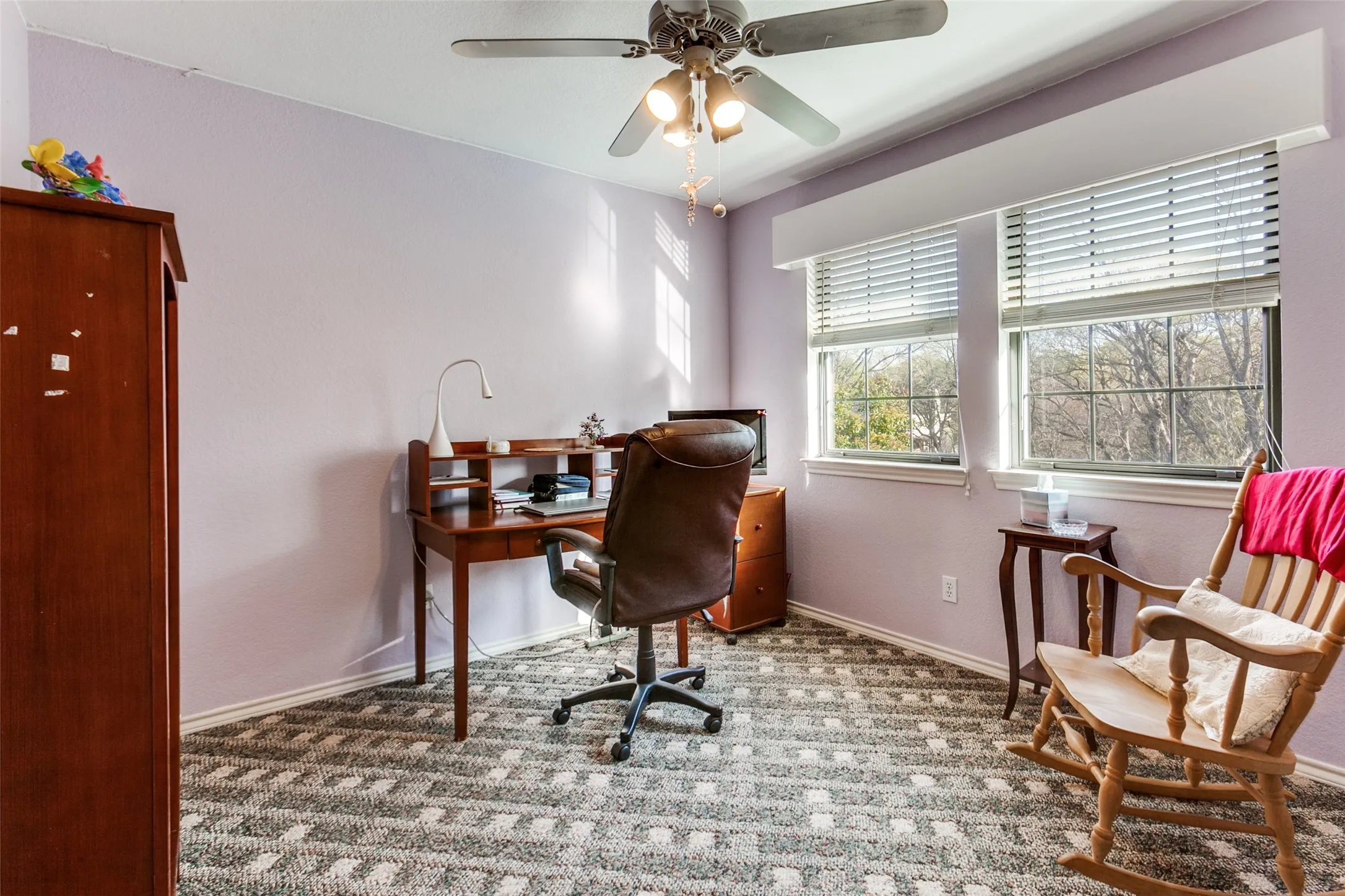 Room featuring patterned carpet flooring, light purple wall paint, and a ceiling fan with integrated lighting