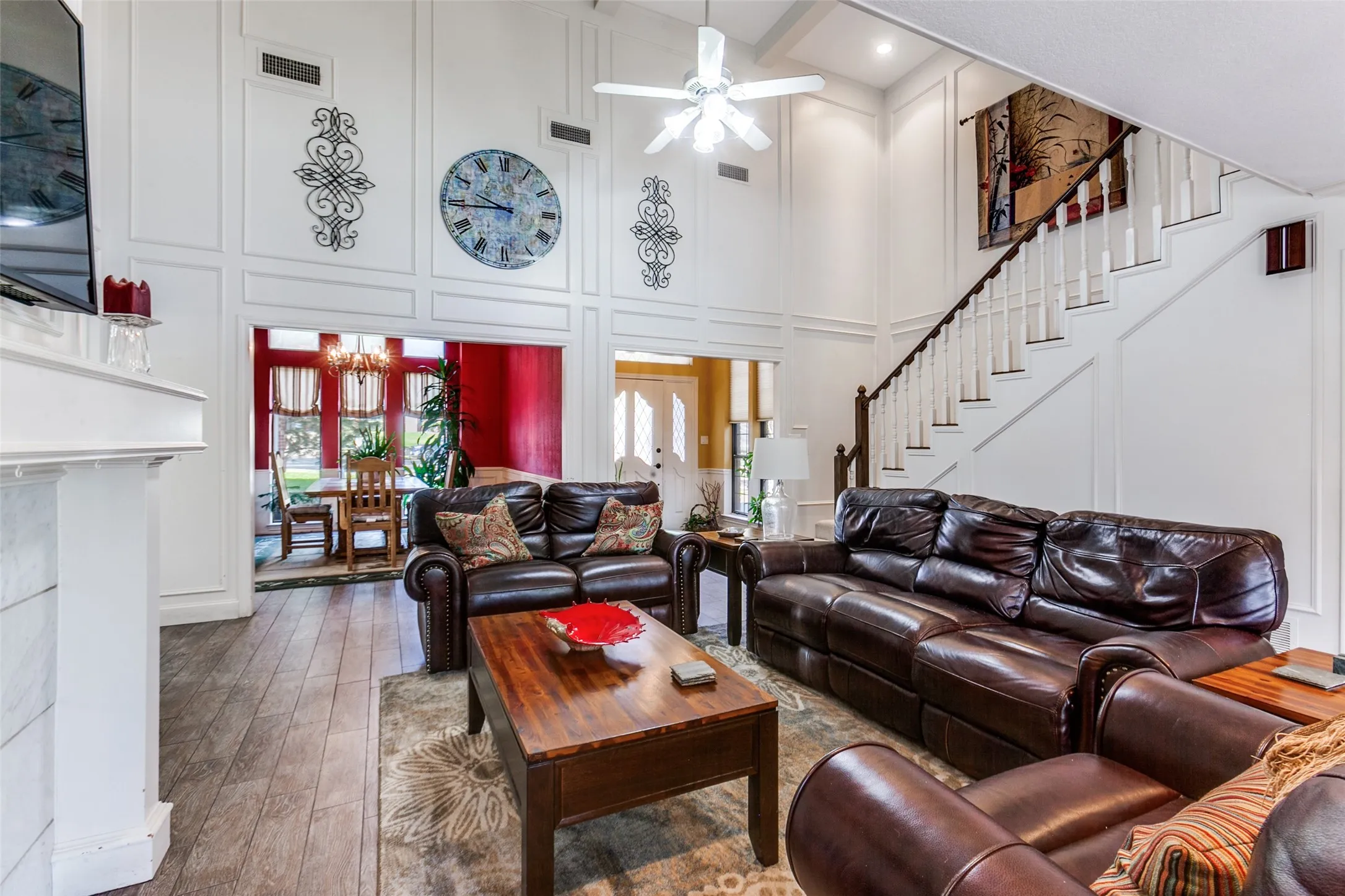 Vaulted ceiling living area featuring white paneled walls and wood-finish flooring