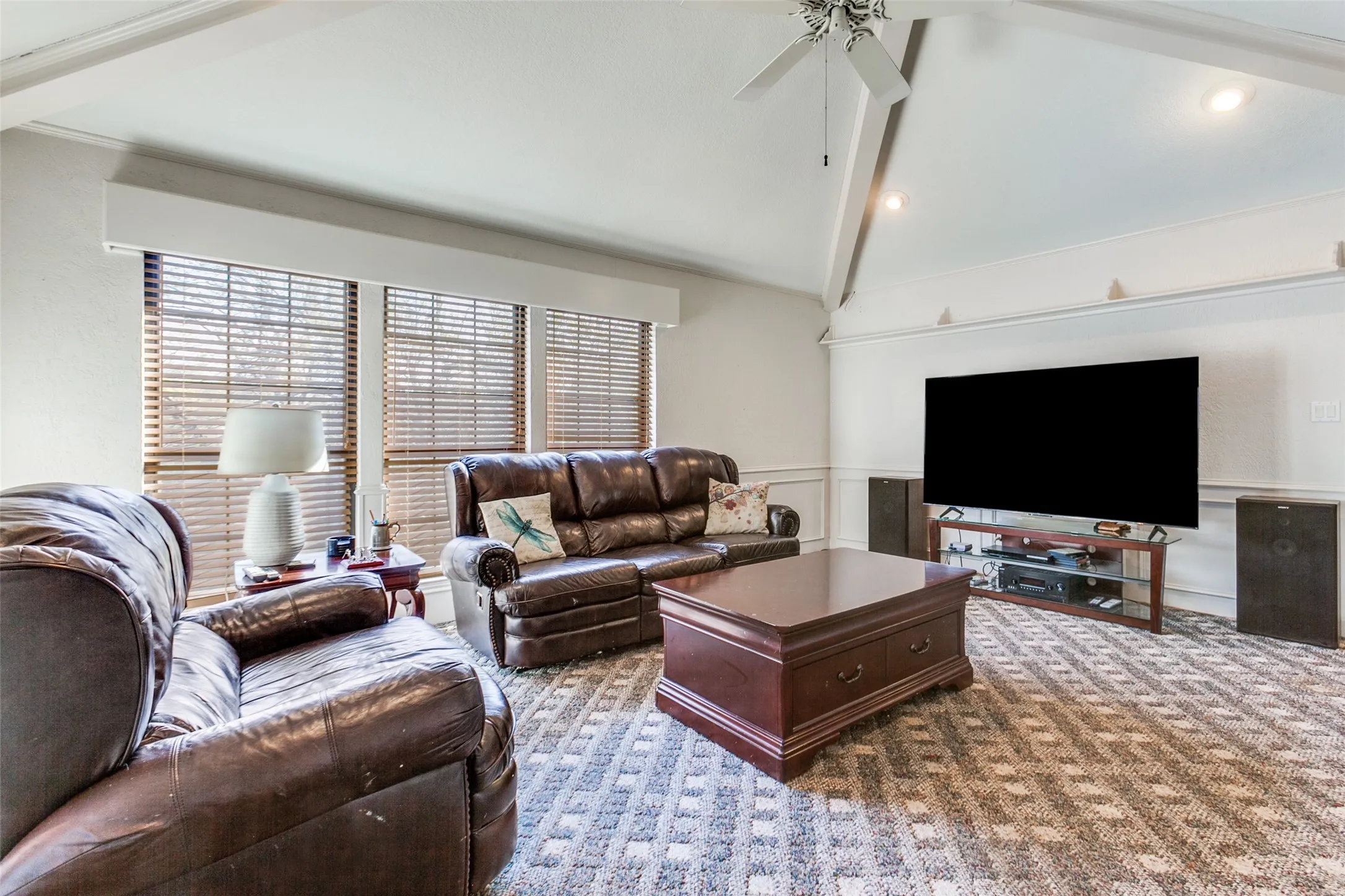 Vaulted ceiling with exposed beams and a ceiling fan