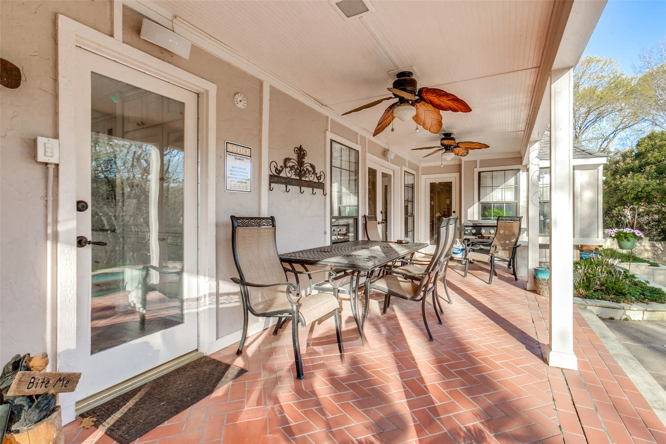 Spacious covered patio featuring brick-patterned flooring and multiple ceiling fans