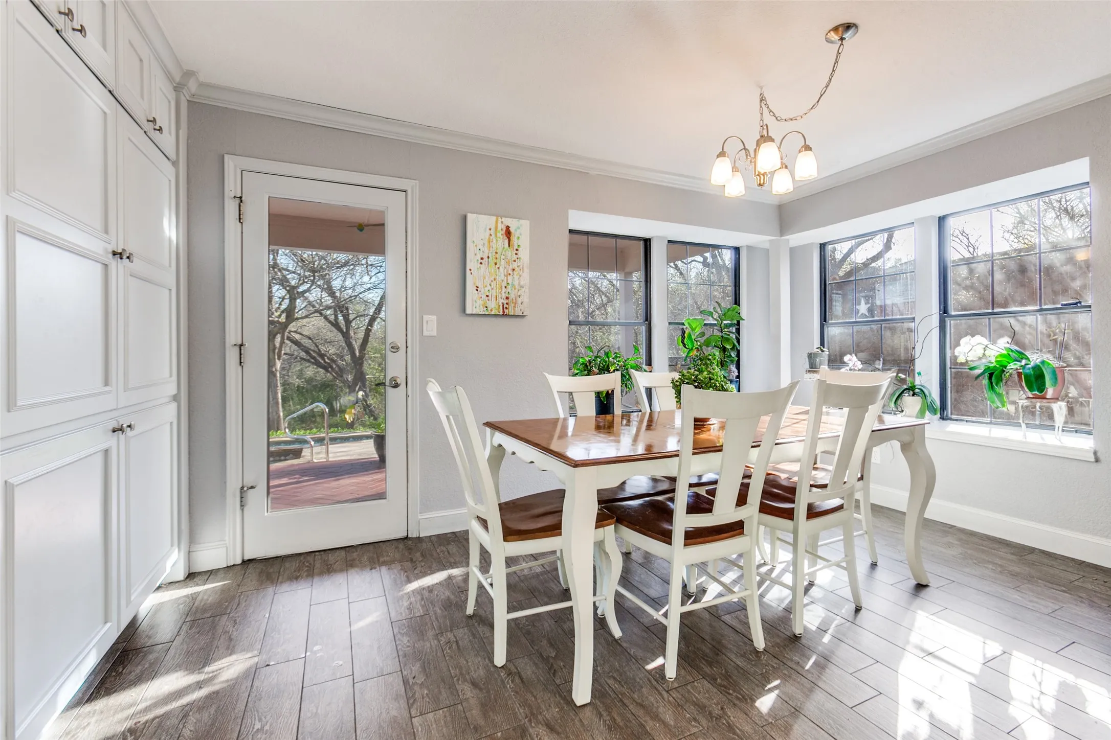 Bright dining area featuring a bay window, wood-finish flooring, recessed built-in cabinetry, and a glass-paneled exterior door