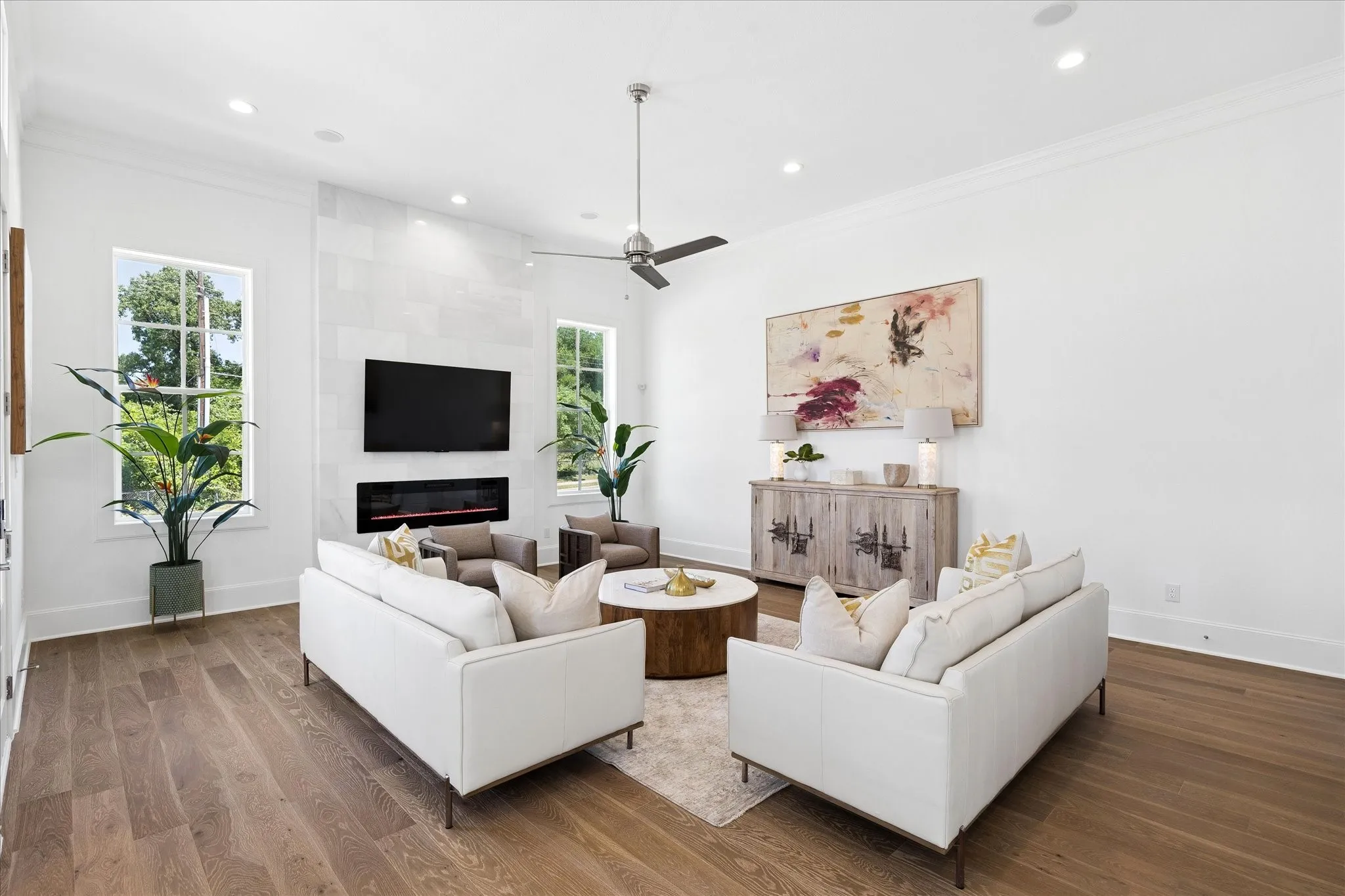 Spacious living area featuring wood-finish flooring, a contemporary fireplace with a stone surround, and an integrated television mount