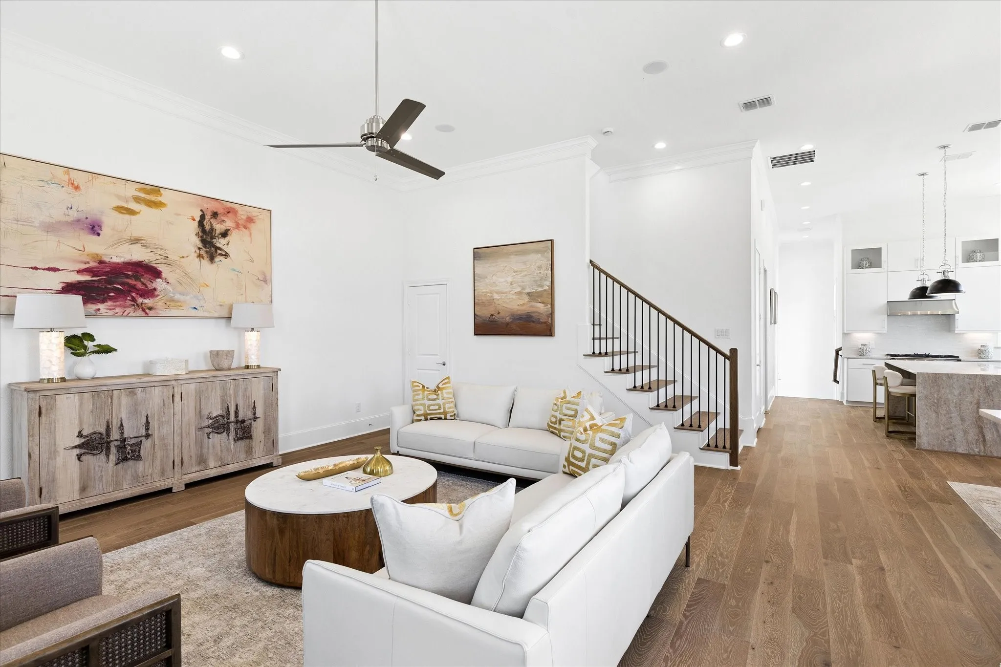 Open-concept living space featuring wide-plank wood-finish flooring, a contemporary ceiling fan, recessed lighting, and crown molding
