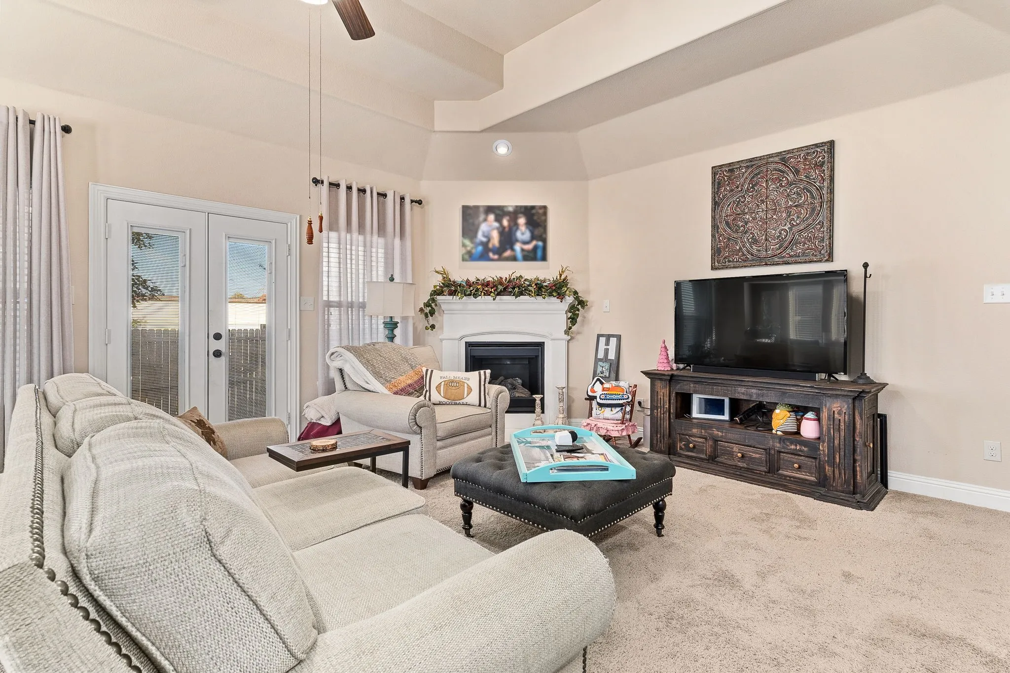 Living room with ceiling fan, light carpet, french doors, and a tray ceiling