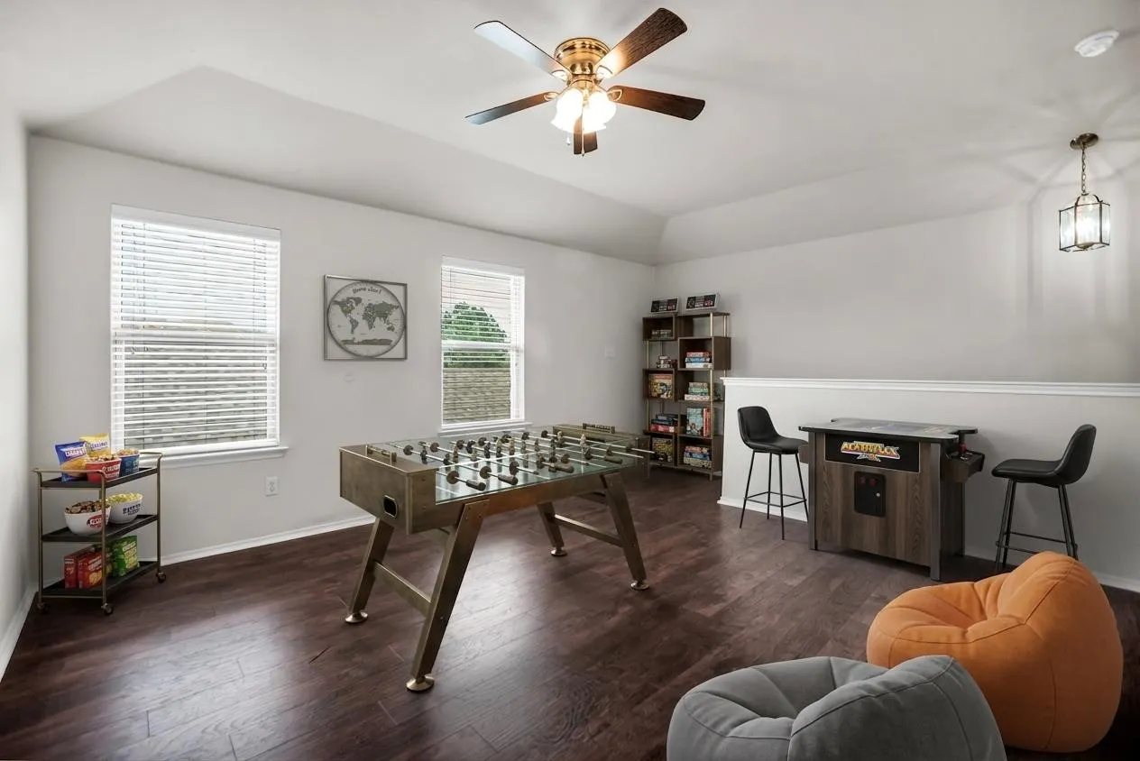 Virtual Staging -Spacious room featuring rich wood-finish flooring, multiple windows with blinds, a ceiling fan with integrated lighting, and a pendant light fixture