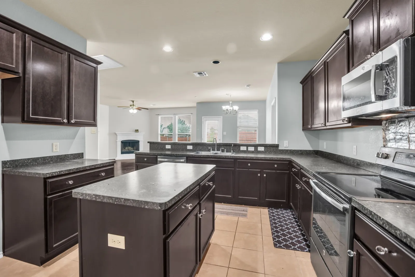 Kitchen featuring dark wood cabinetry, a central island, and stone-finish countertops