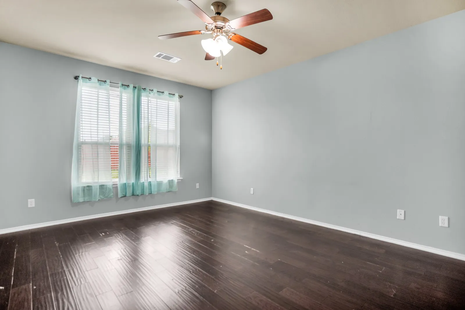 Spacious room featuring dark wood-finish flooring, light gray wall paint, and white trim