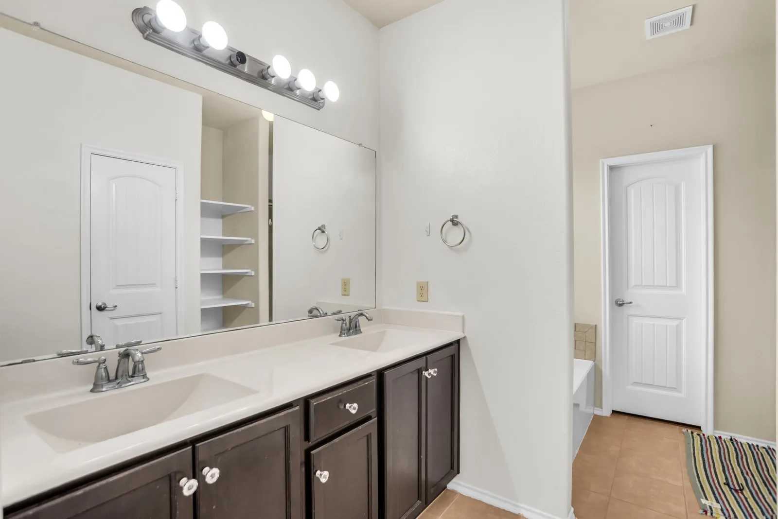 Dual vanity with integrated sinks, dark wood-finish cabinetry, and a full-width mirror