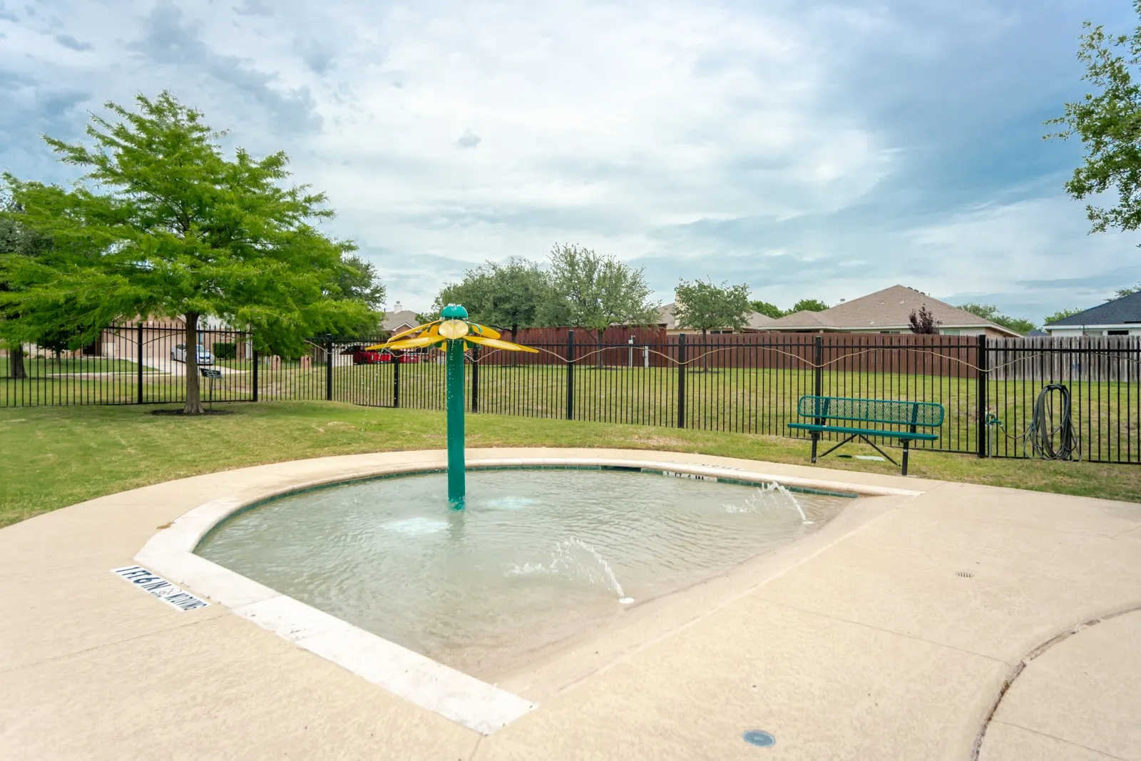 Splash pad with decorative water feature, surrounded by a concrete deck