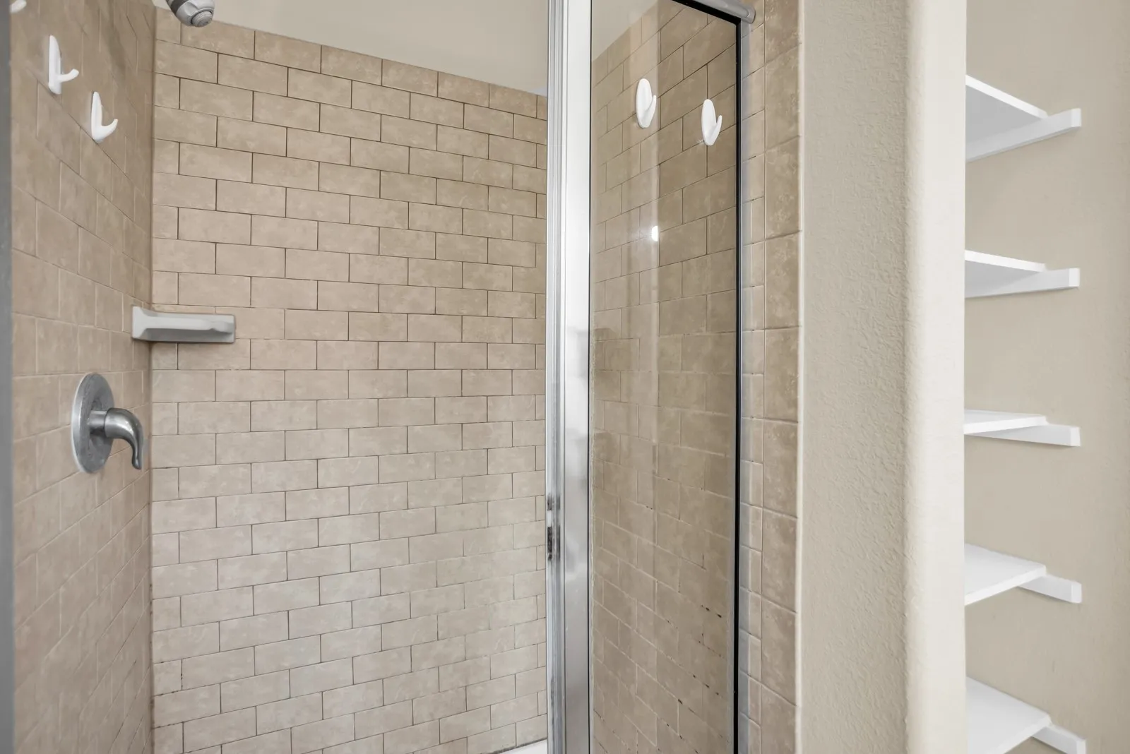 Shower enclosure featuring subway tile surround, brushed nickel fixtures, and a glass panel door