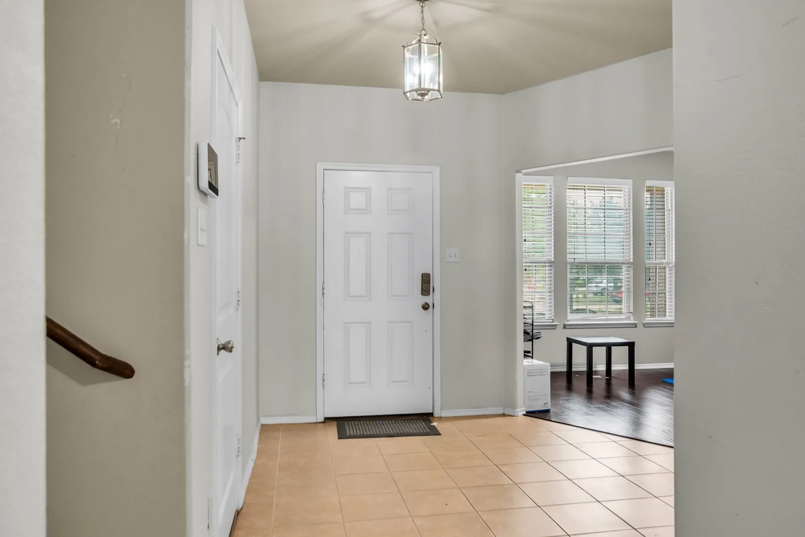 Foyer featuring light-toned tile flooring, a four-panel entry door, and a hanging ceiling light fixture