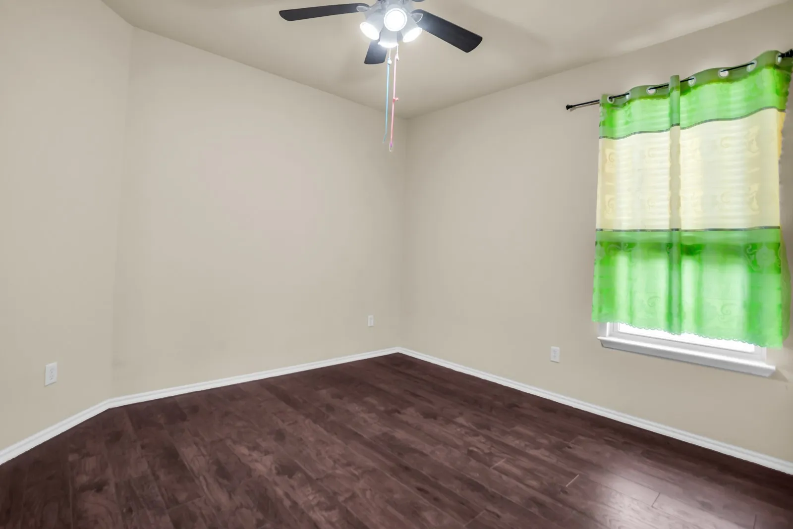 Interior room featuring wood-finish flooring, light-toned walls, and a ceiling fan with integrated lighting