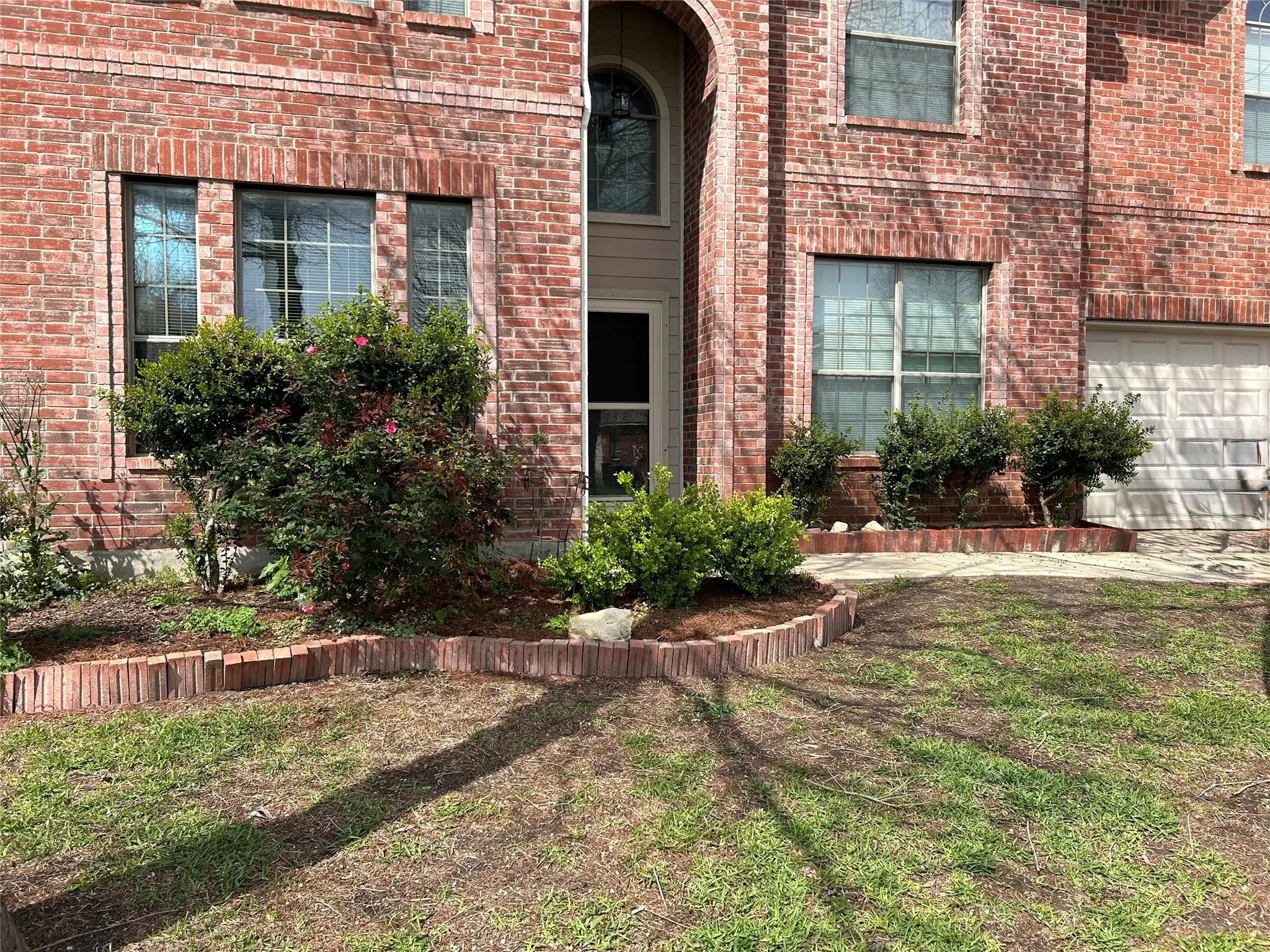 Two-story brick exterior featuring multiple windows and an attached garage