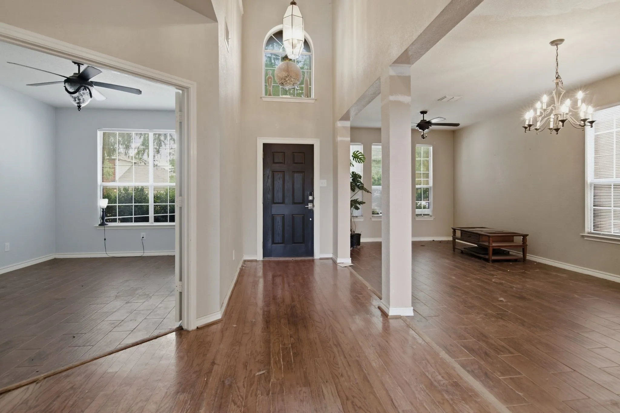 Two-story entryway featuring a dark paneled front door, an arched window with decorative grille, and a hanging light fixture