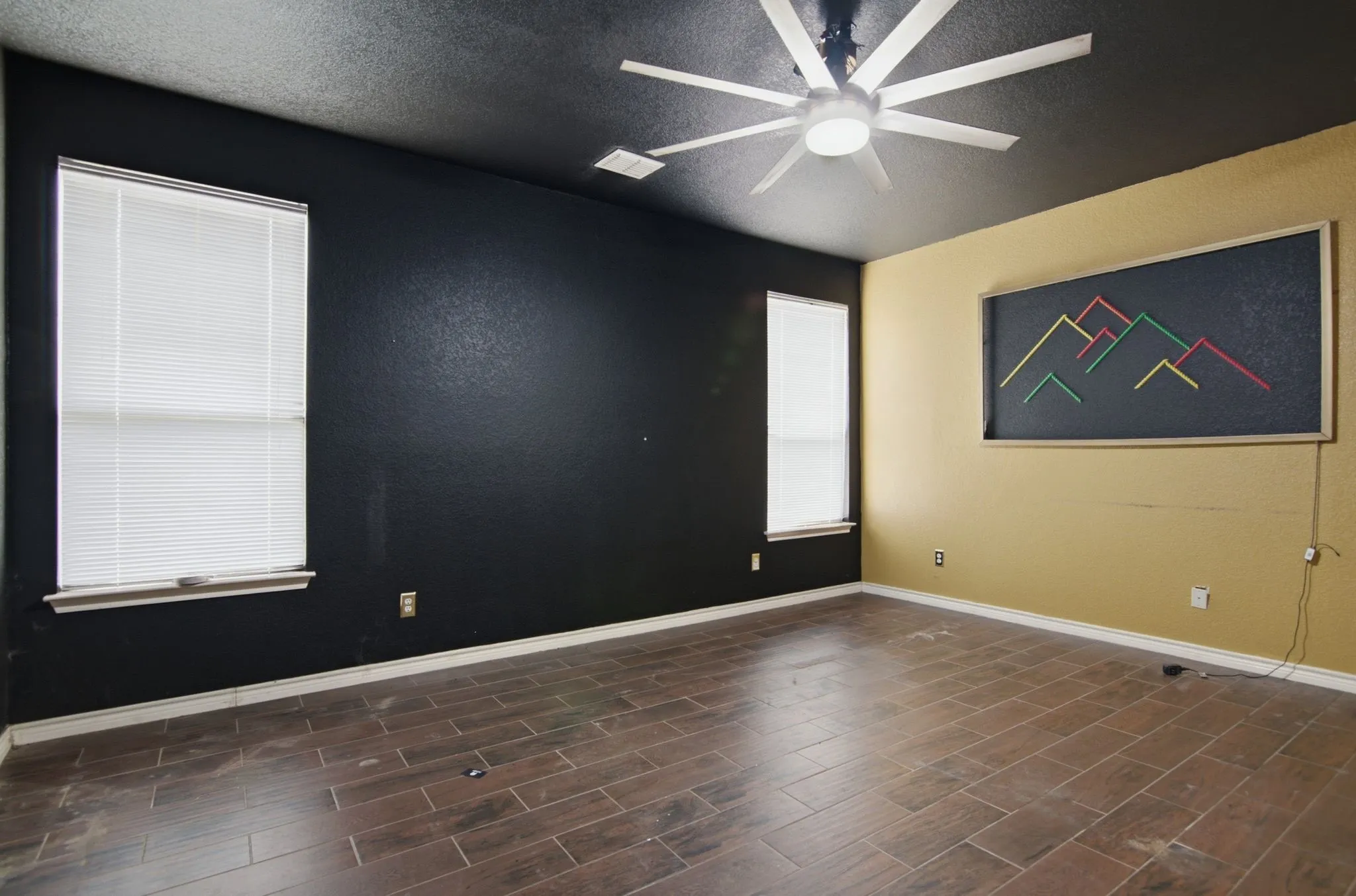 Spacious interior room featuring wood-finish tile flooring and a ceiling fan with integrated lighting