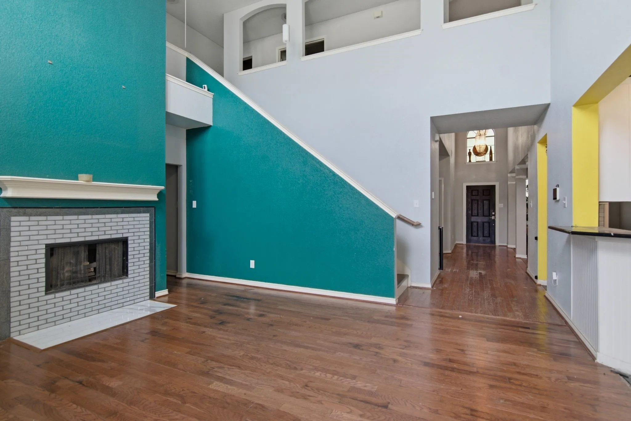 Two-story entry foyer with hardwood flooring and a prominent fireplace featuring a white brick surround and mantel