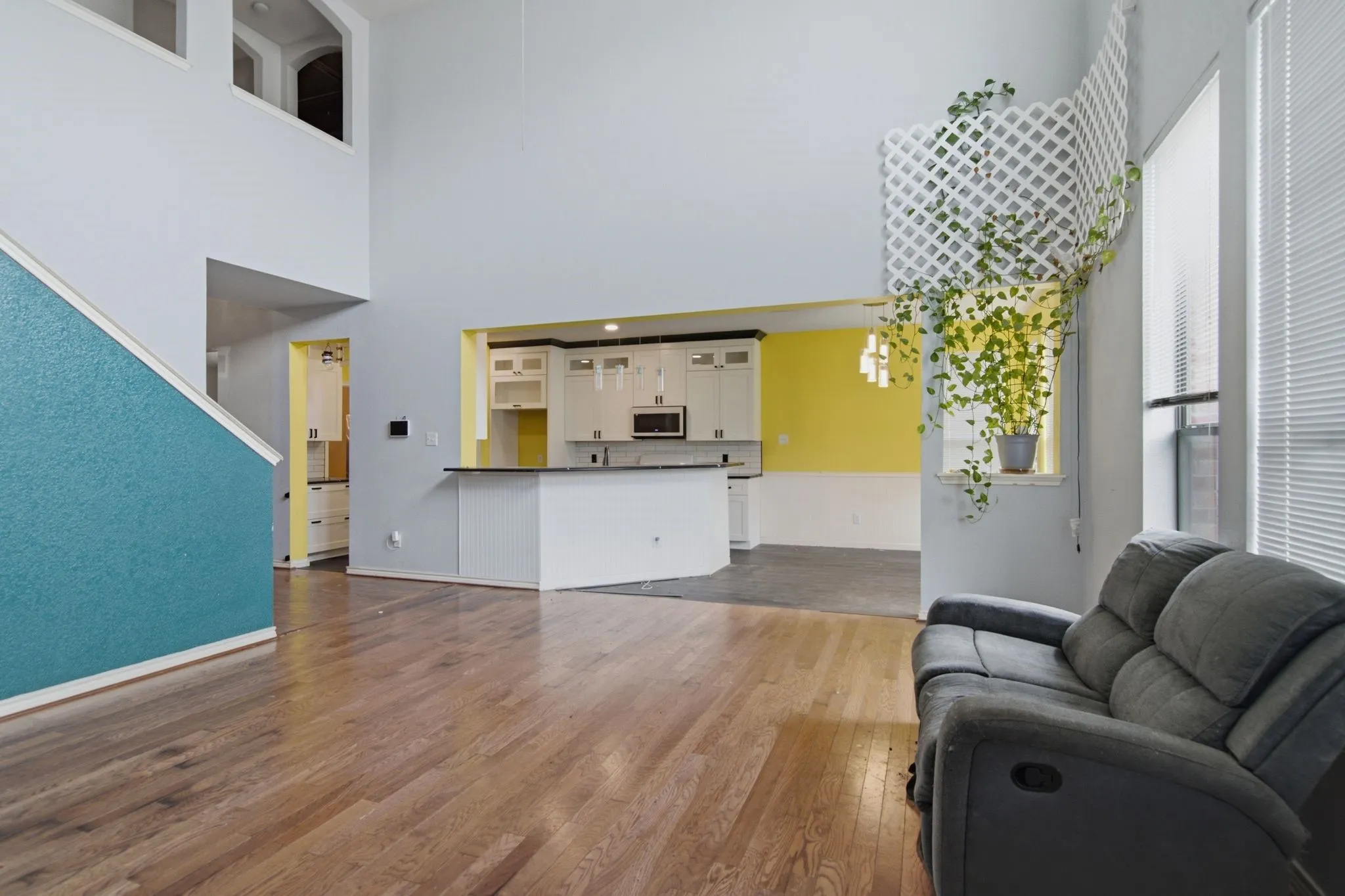 Spacious open-concept living area featuring wood-finish flooring, high ceilings, and a kitchen pass-through