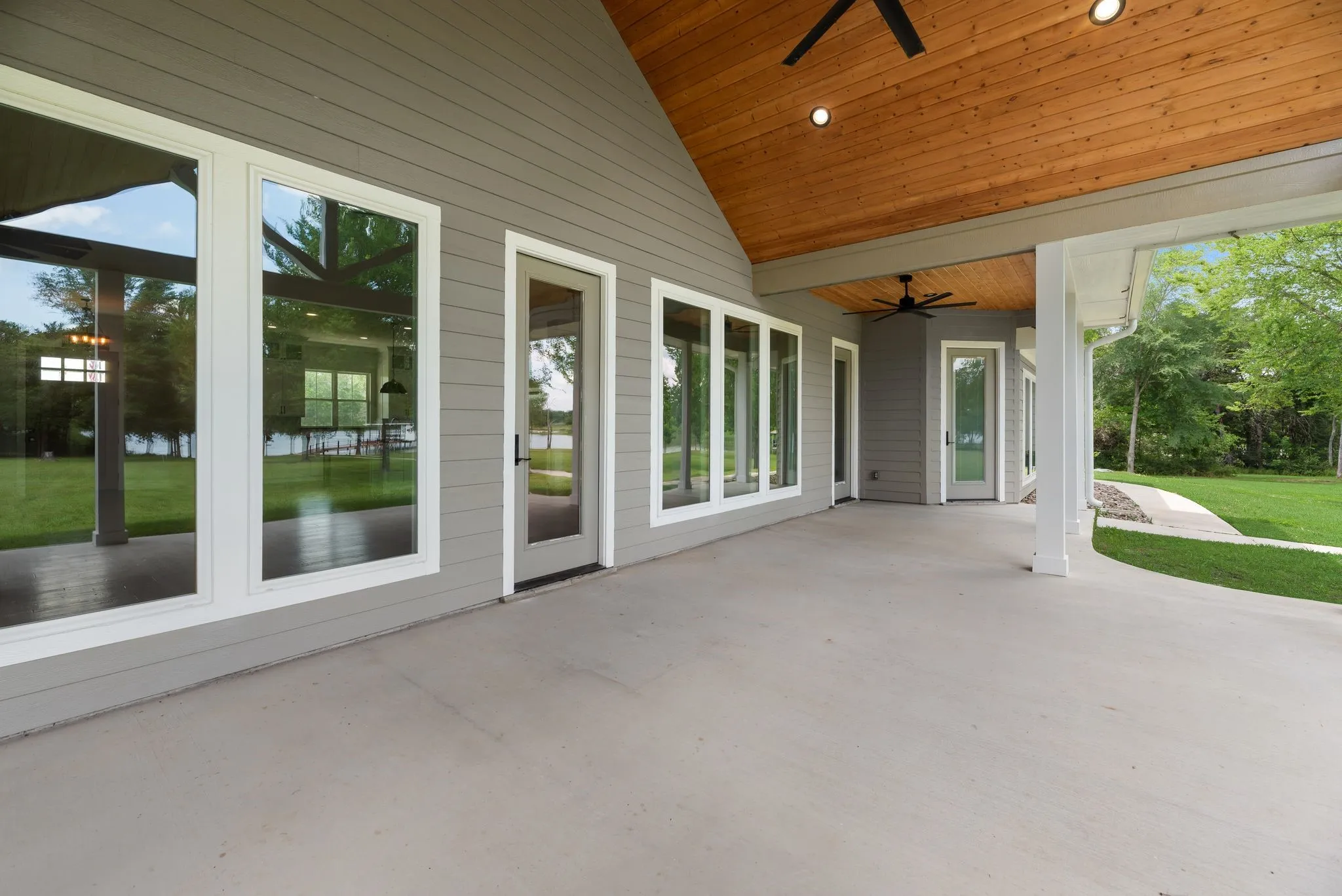 Covered back patio overlooking mature trees, open lawn, and lakefront acreage.
