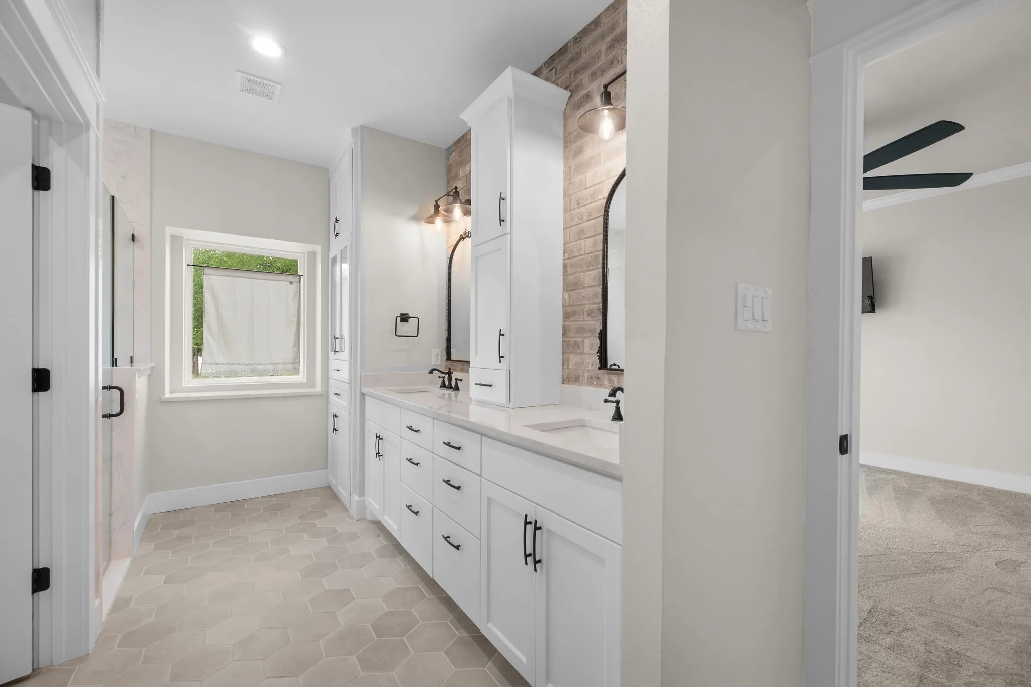 Spacious second primary bathroom with dual vanity and walk-in closet access.