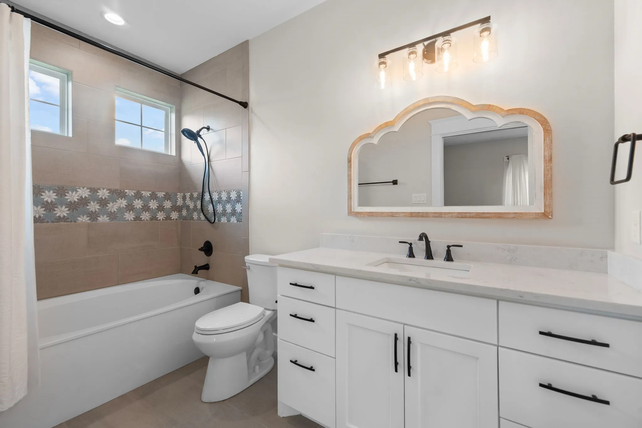 Ensuite bath with tub-shower combo, dual sinks, and decorative mirror.